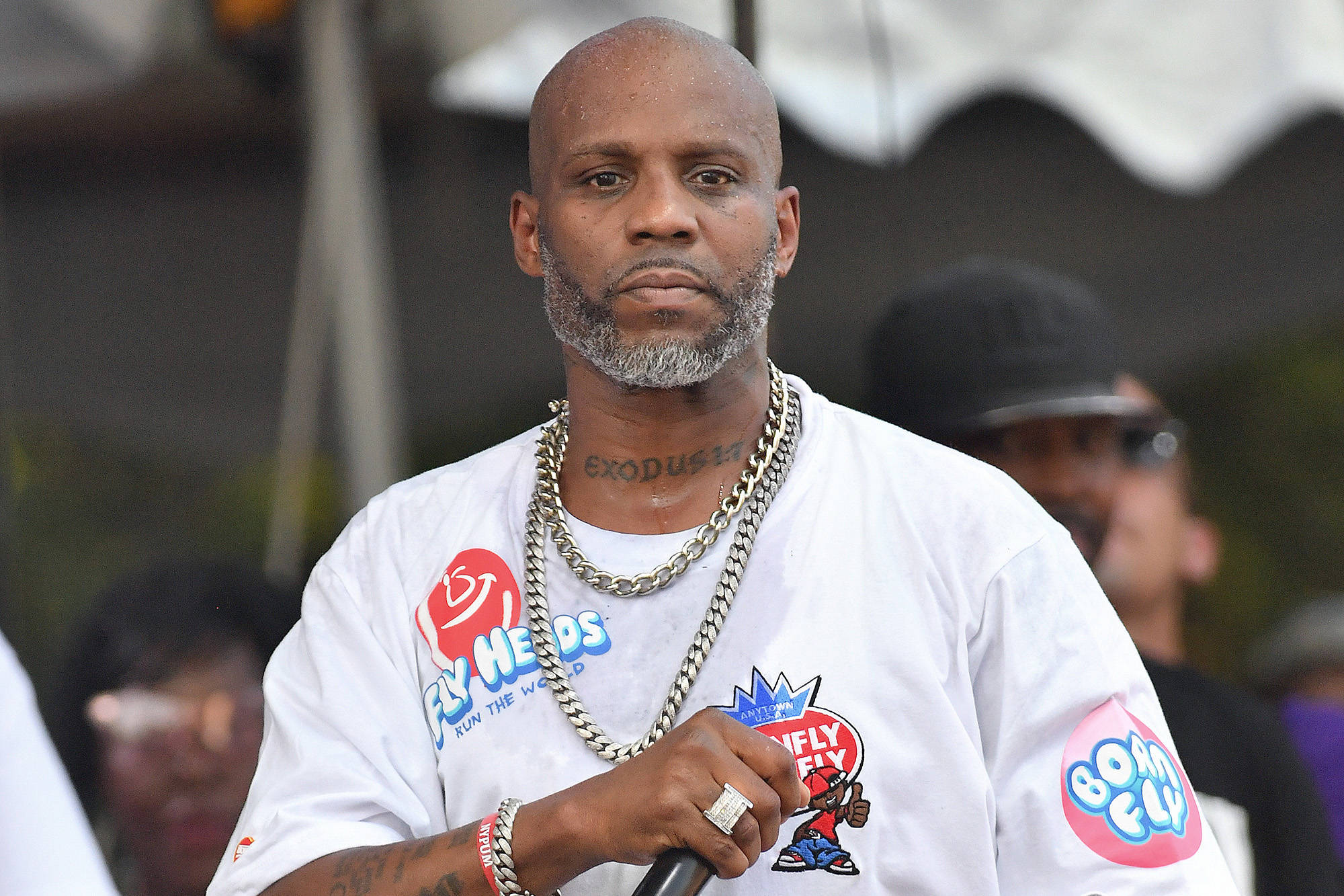 Dmx 桌布 壁紙 — 一位禿頭灰鬍鬚的男人穿著白色圖案T恤和粗鏈條項鍊，在戶外拿著麥克風。