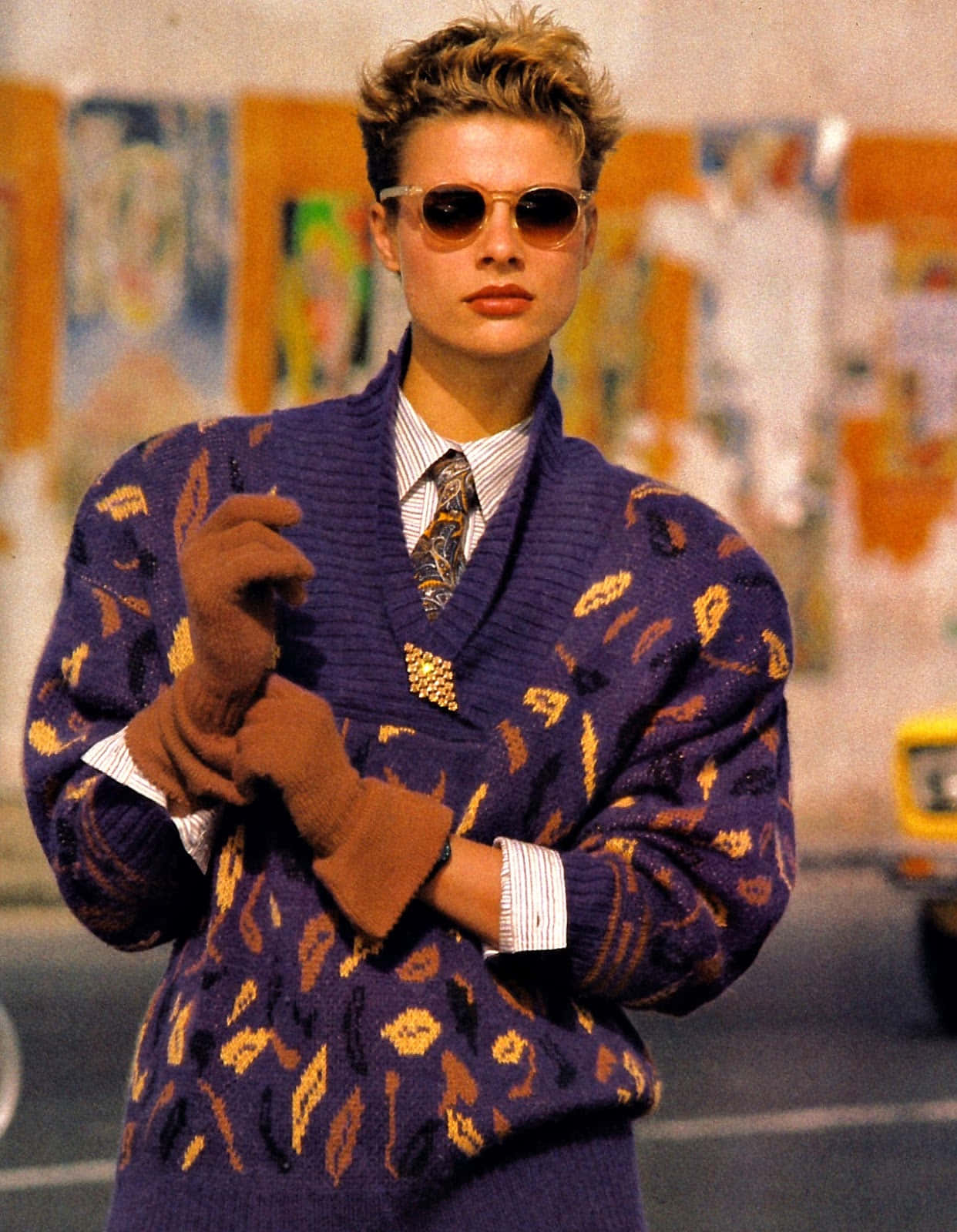 1980s 桌布 壁紙 — 一位穿著1980年代時尚的女性，身穿紫色圖案開襟毛衣、棕色手套和太陽眼鏡，同時調整她的手套。