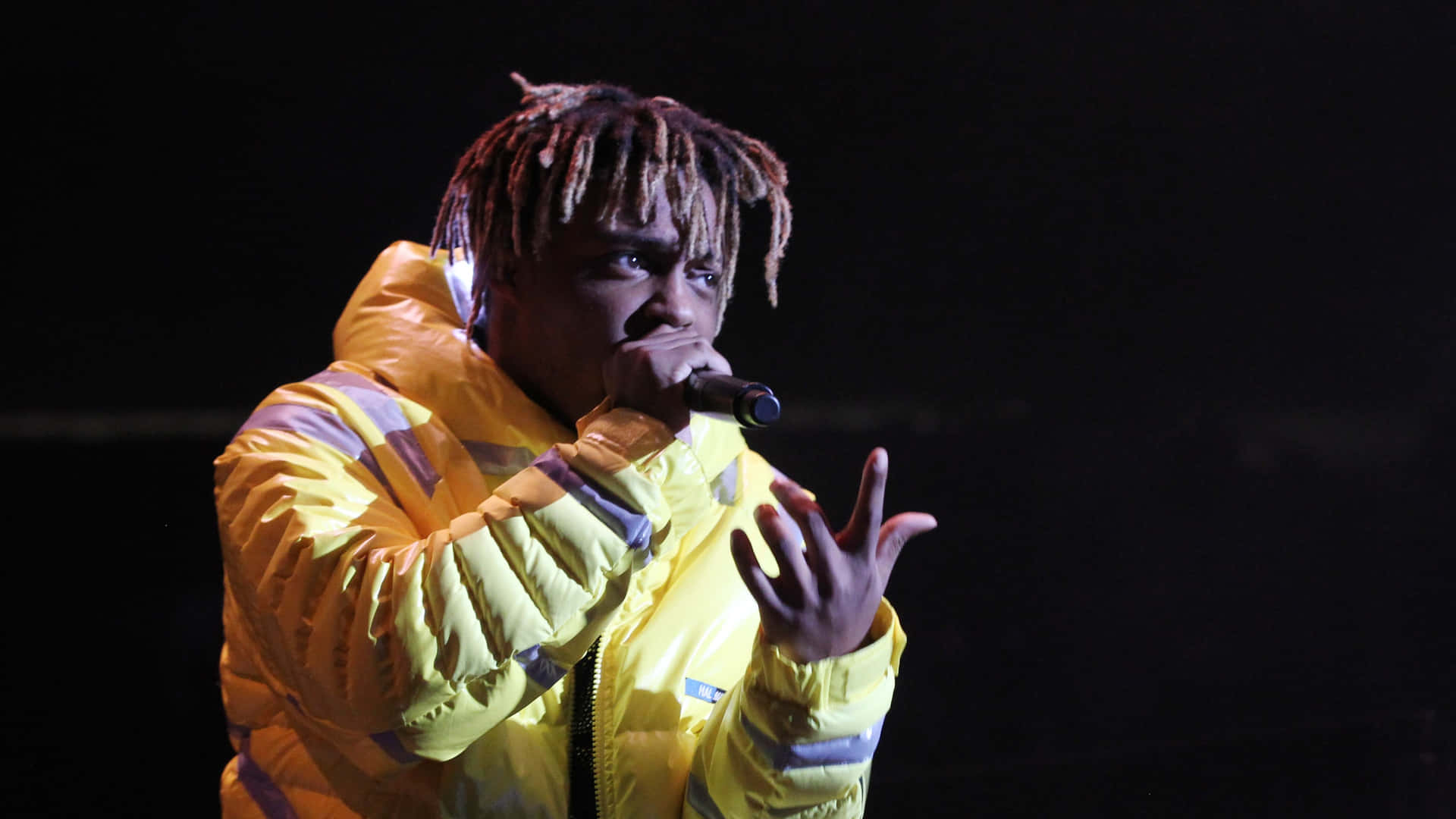 黃色外套歌手在舞台上用麥克風表演 — Juice Wrld 壁紙
