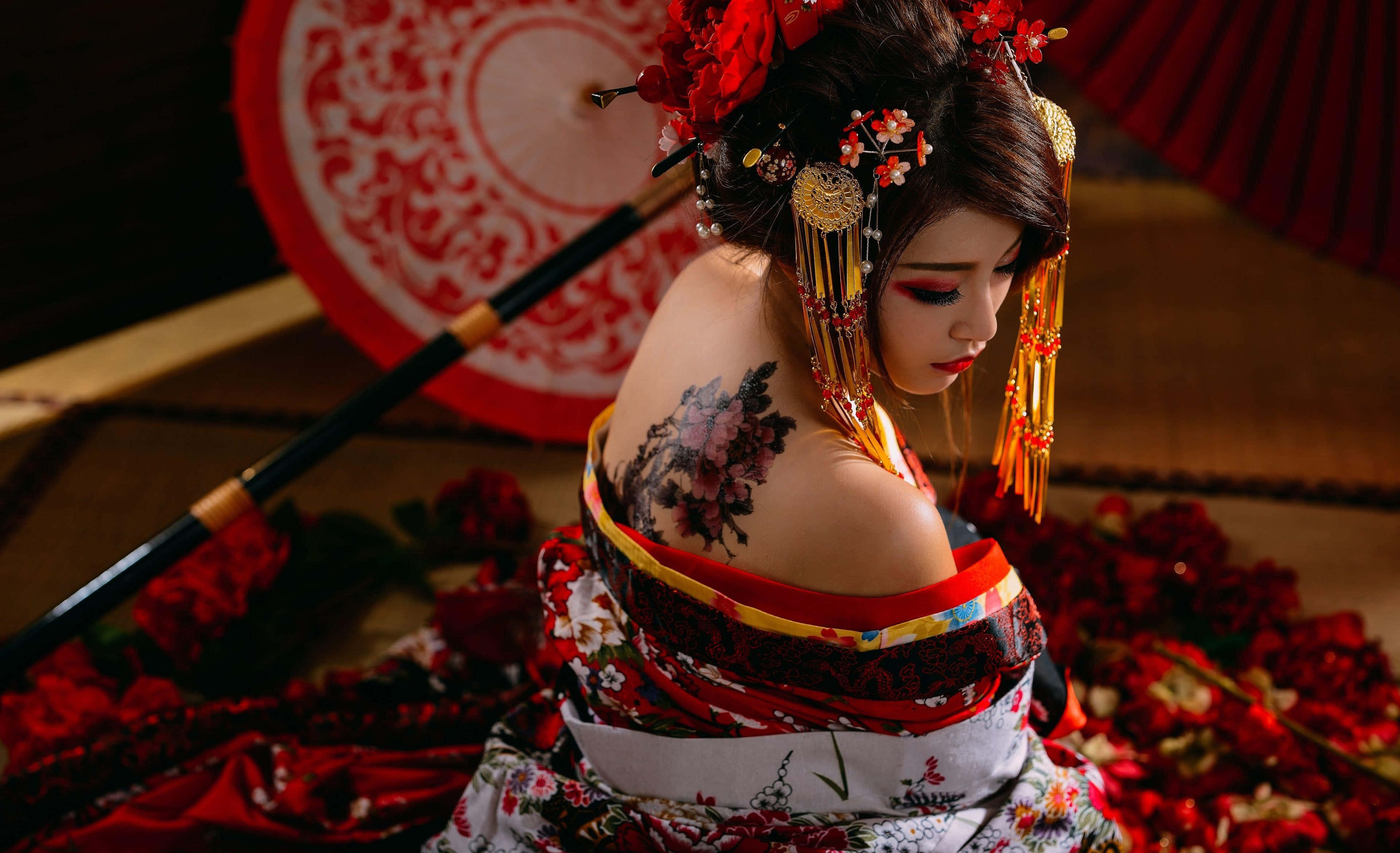 Tattoo 桌布 壁紙 — 一位穿著傳統日本服飾的女性，帶有花卉紋身和紅色配飾，坐在紅色花瓣中。