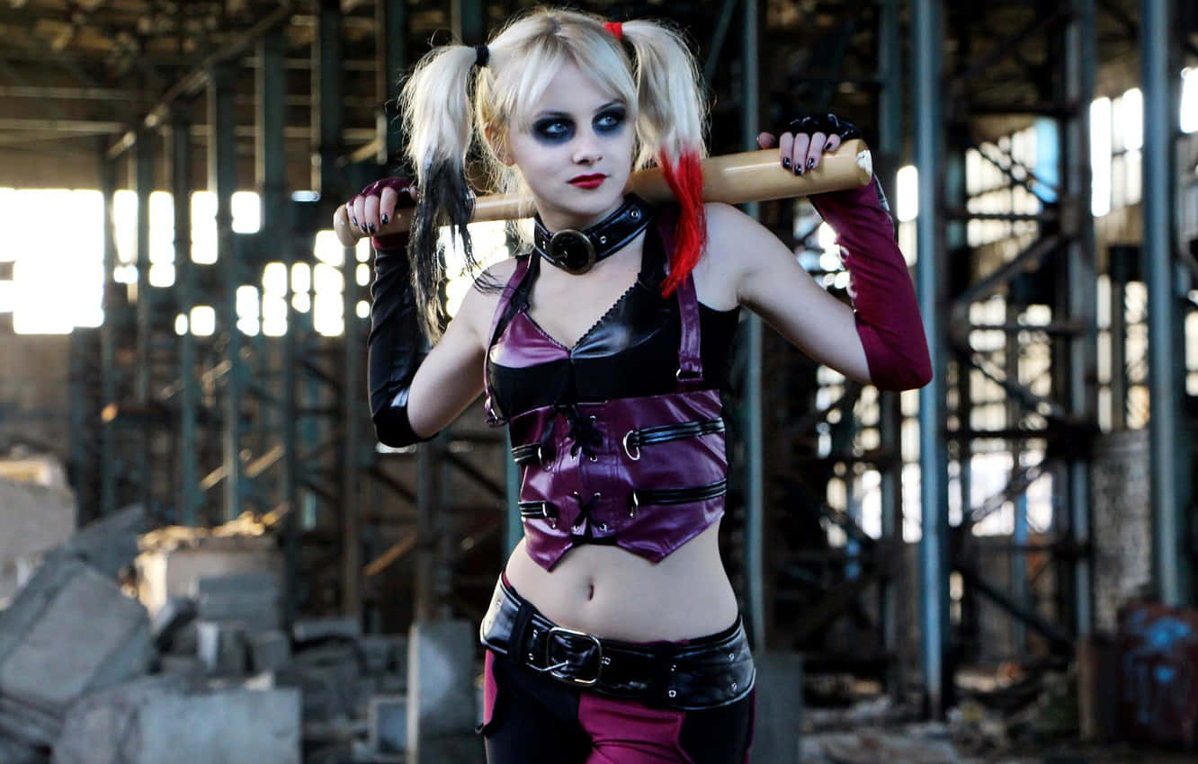 Harley Quinn Cosplay 桌布 壁紙 — 一位穿著哈莉·奎茵服裝、紮著辮子並拿著蝙蝠的女性，在廢棄倉庫中握著棒球棍。