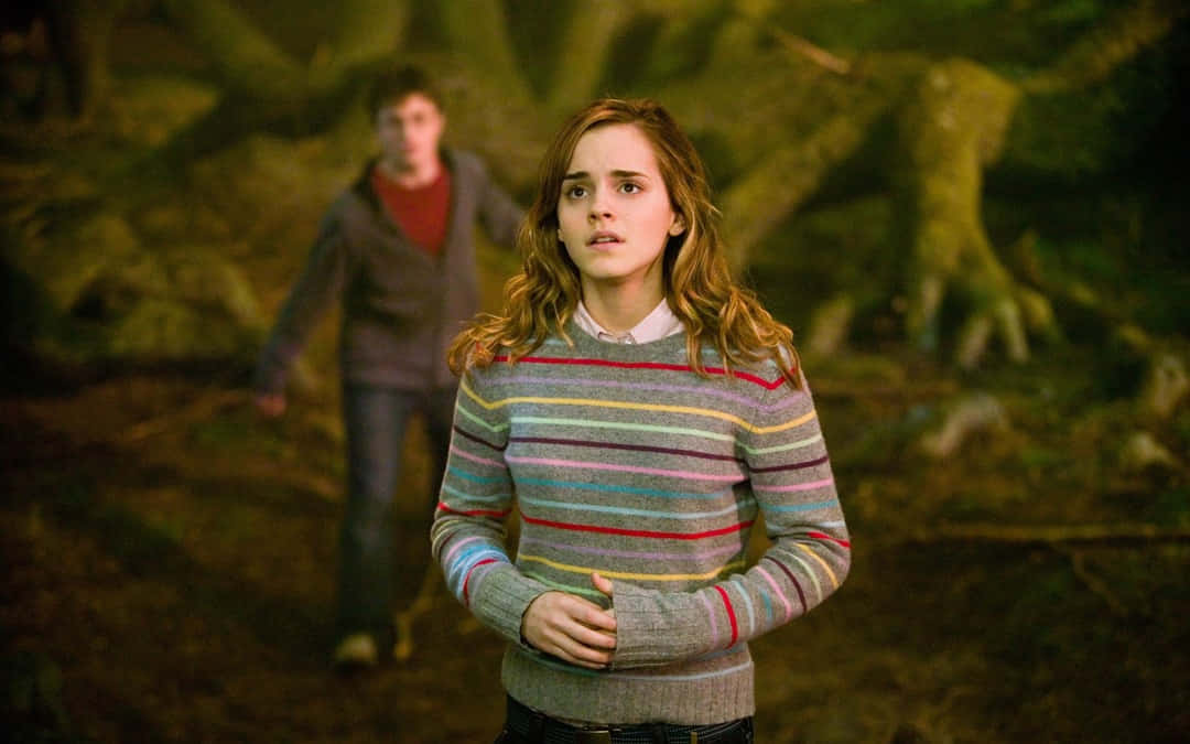 The Goblet Of Fire 桌布 壁紙 — 一位穿著彩色條紋毛衣的年輕女子在昏暗的森林中保持警覺，一個模糊的身影正從她身後靠近。