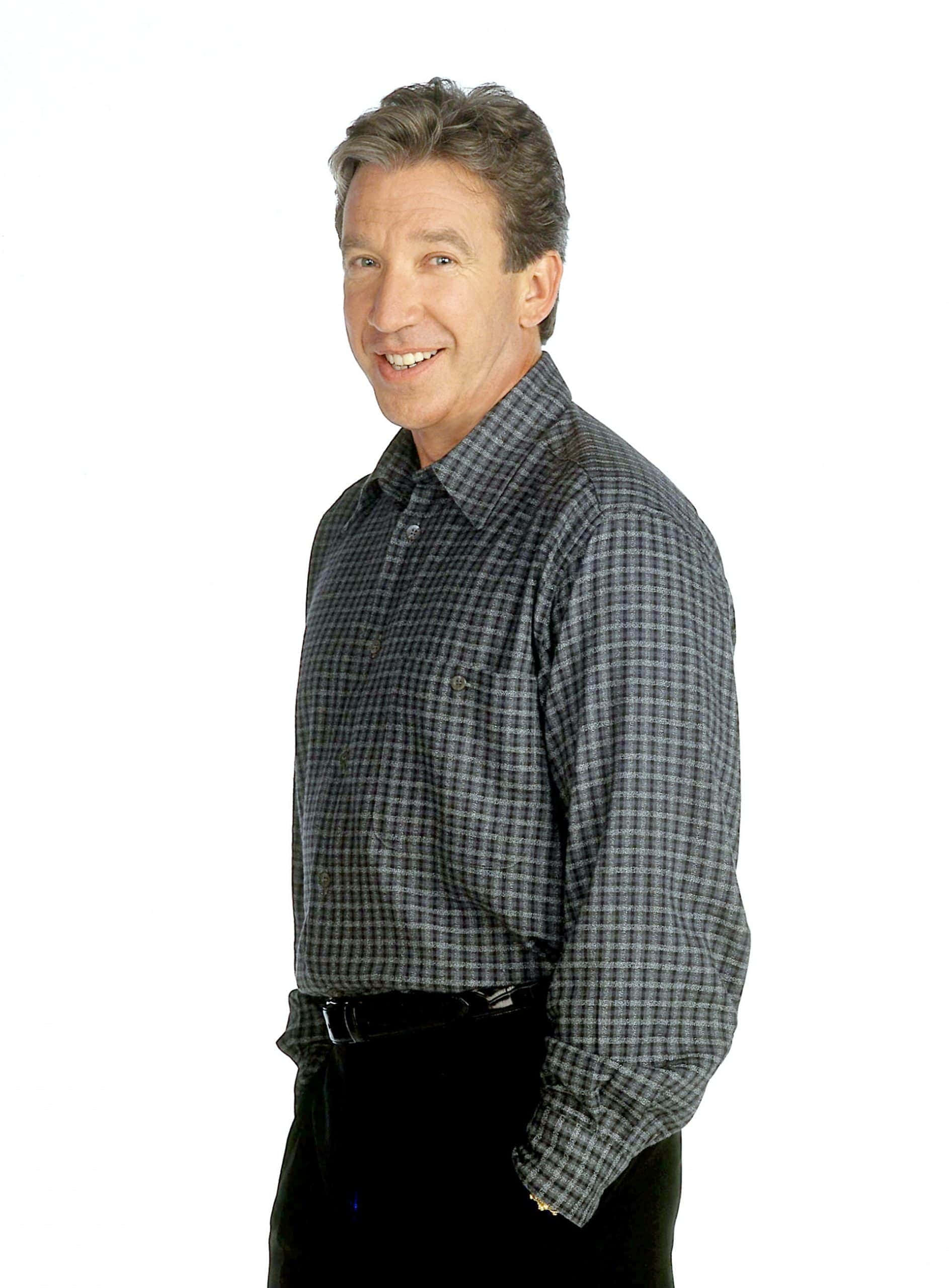 Tim Allen 桌布 壁紙 — 一位穿著格紋襯衫的開朗中年男子在純白背景前溫暖地微笑。