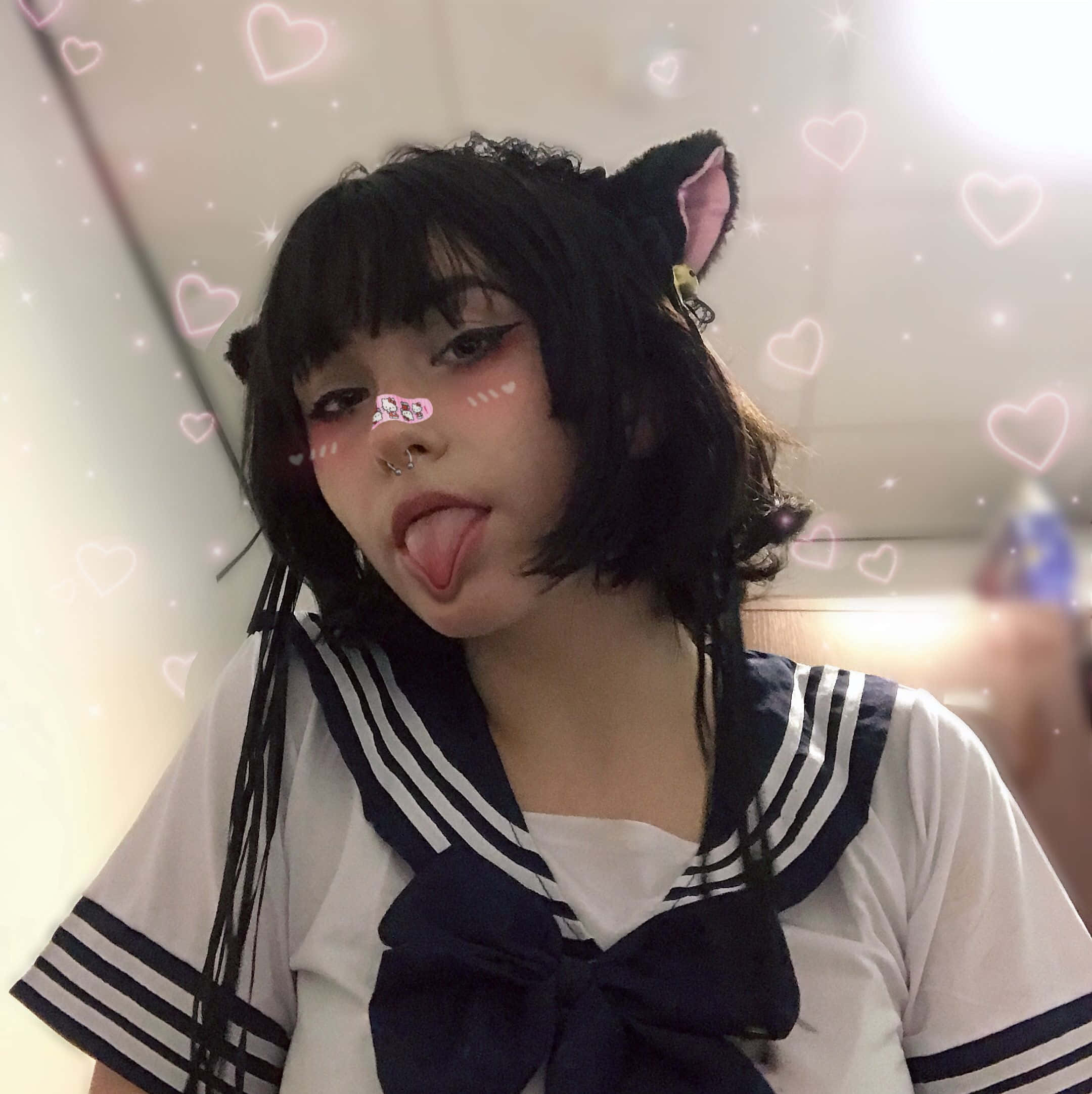垃圾美學 桌布 壁紙 — 一位穿著水手服、戴著貓耳的年輕女性，在閃爍的心形和火花背景下頑皮地伸出舌頭。