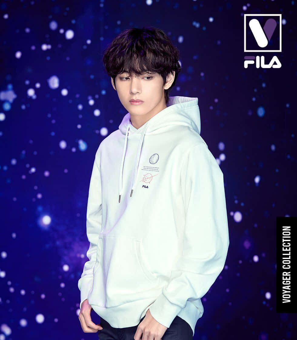 Bts Endorsements 桌布 壁紙 — 一位穿著淺色連帽衫的年輕男子站在閃爍的宇宙藍色背景前，帶有FILA品牌標誌。