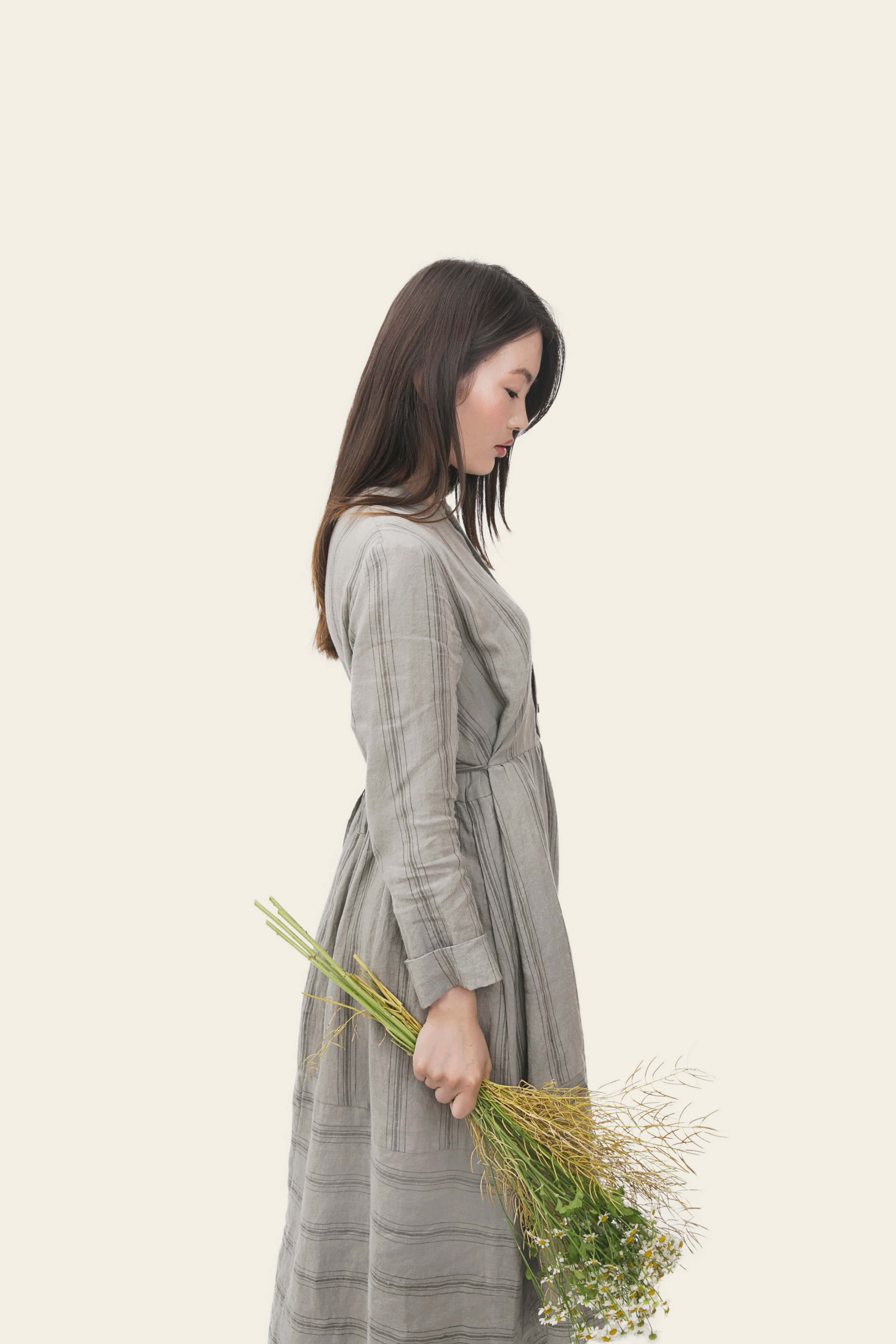 korean 桌布 壁紙 — 一位穿著灰色條紋連衣裙的女性，在柔和的米色背景前拿著一束乾草。