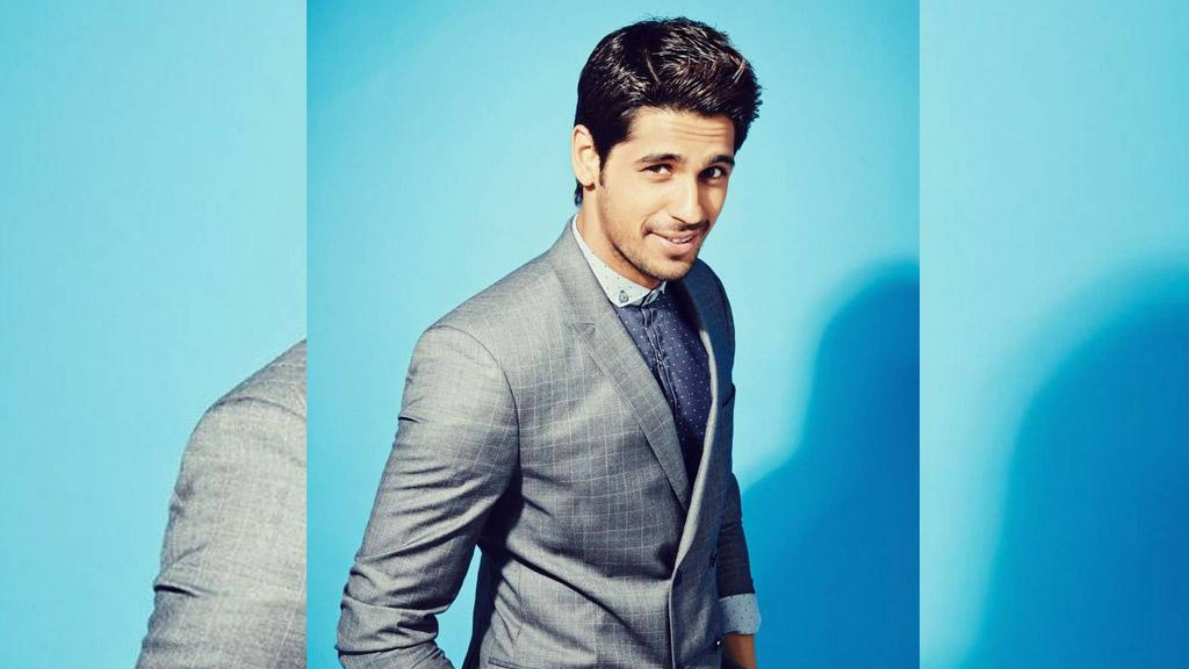 Sidharth Malhotra 桌布 壁紙 — 一位穿著灰色西裝的時尚男士在充滿活力的藍色工作室背景前自信微笑，帶有柔和陰影。