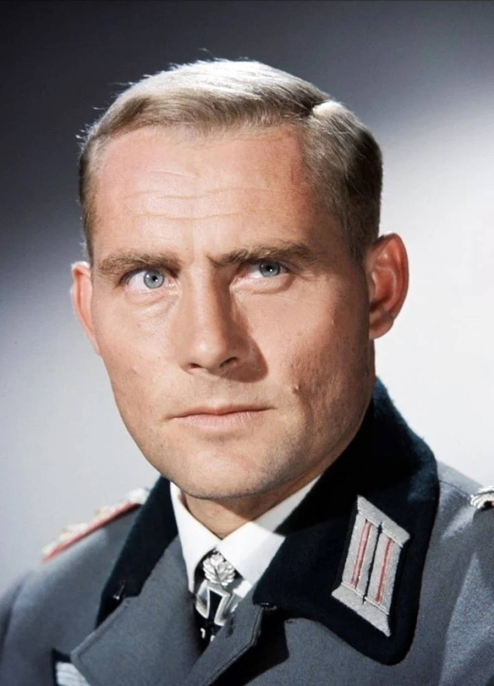 Celebrity 桌布 壁紙 — 一位穿著灰色軍裝、帶有徽章的嚴肅男子，在柔和的漸變背景前專注地凝視。
