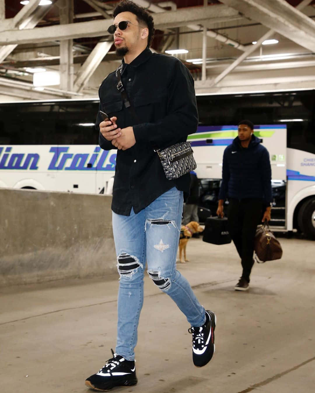 Dillon Brooks 桌布 壁紙 — 一位穿著破洞牛仔褲和太陽眼鏡的時尚男士自信地走過體育場停車場。