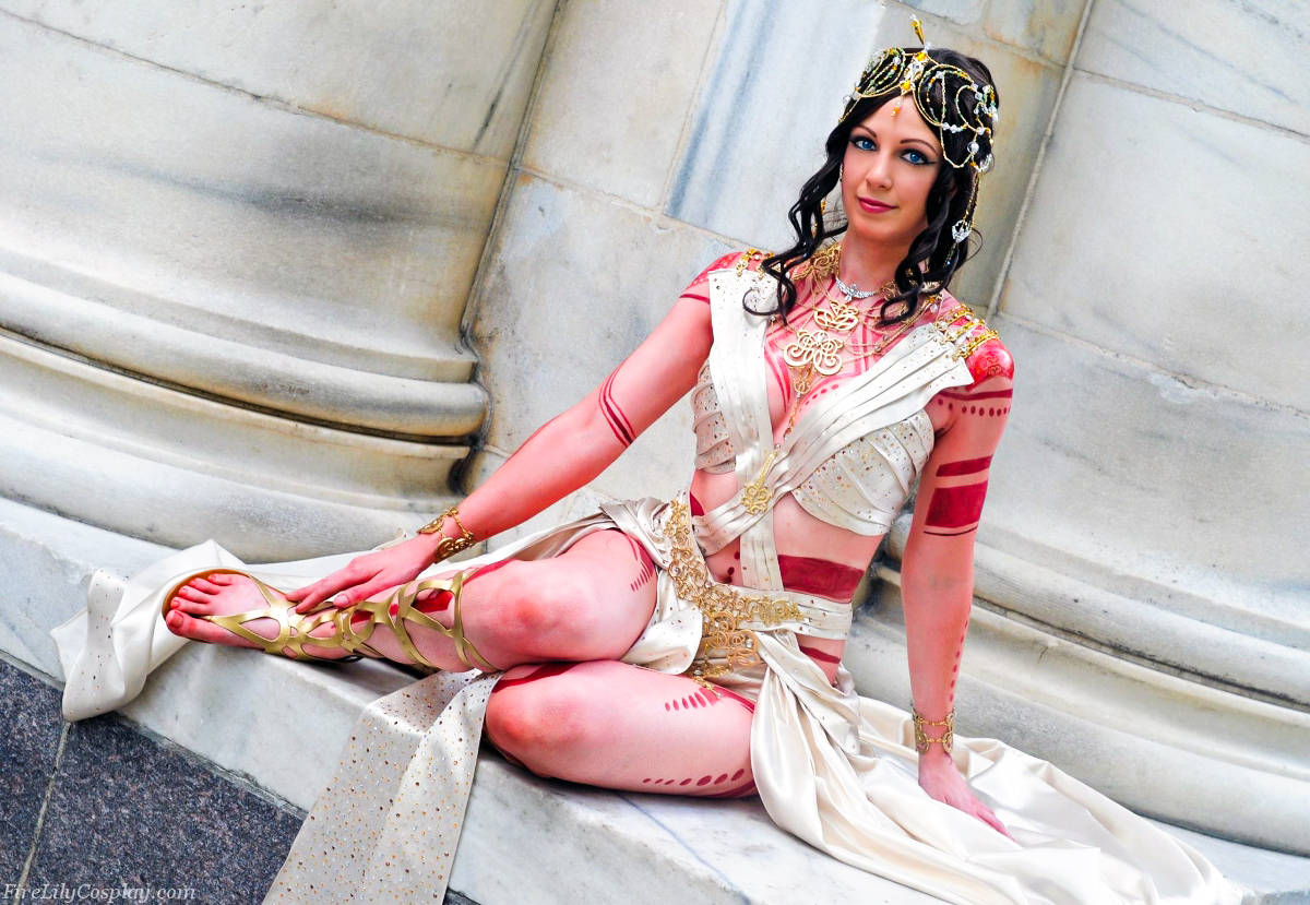 john carter 桌布 壁紙 — 一位穿著精緻古埃及角色扮演服飾的女性，優雅地坐在大理石台階上，佩戴金色珠寶和紅色身體彩繪。