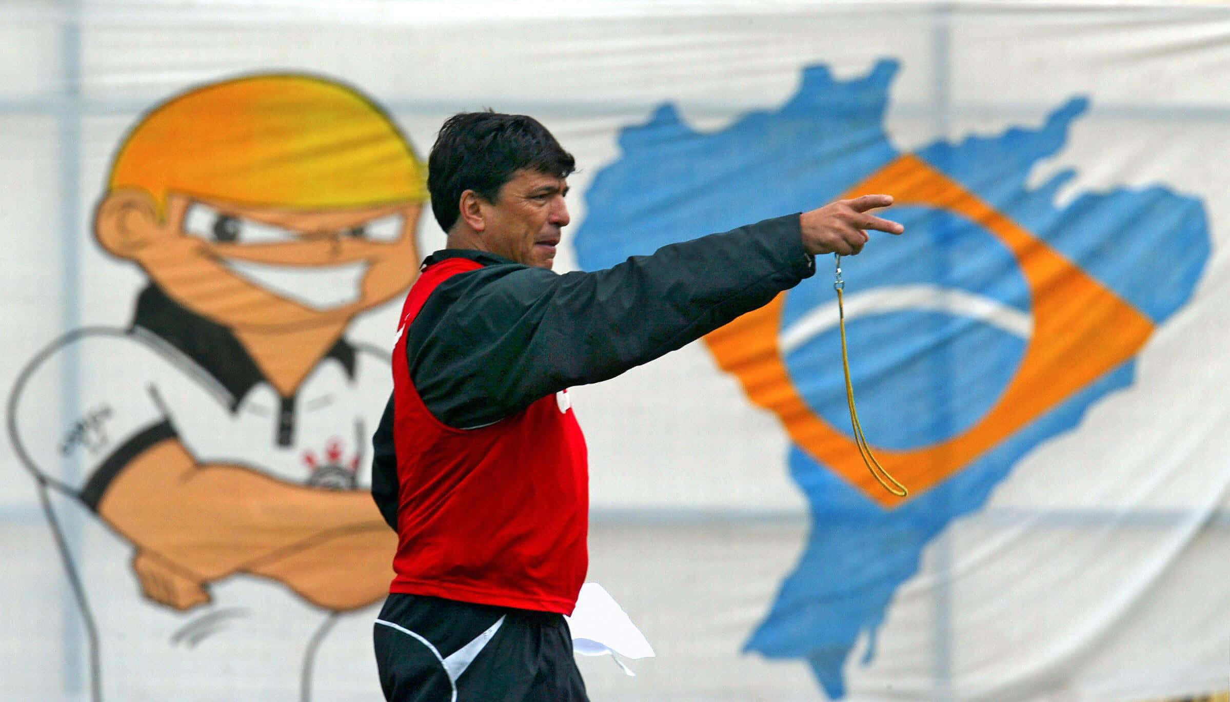 Argentina National Football Team 桌布 壁紙 — 一位穿著紅色背心的教練在網球訓練期間，與卡通吉祥物和巴西地圖背景一起做手勢。