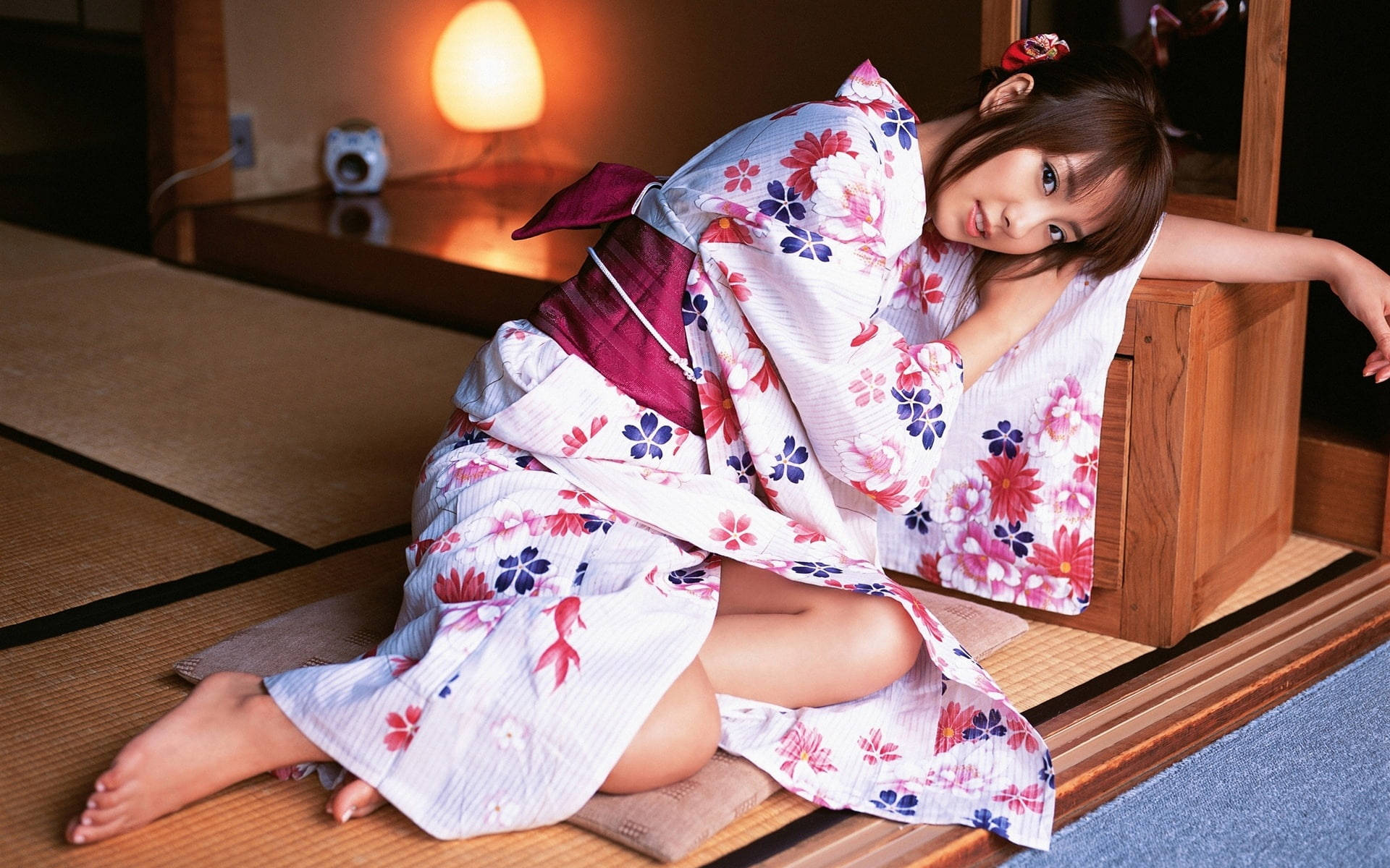 Cute Girls 桌布 壁紙 — 一位穿著花卉圖案浴衣的年輕女性，在溫暖燈光的傳統日式房間的榻榻米上休息。