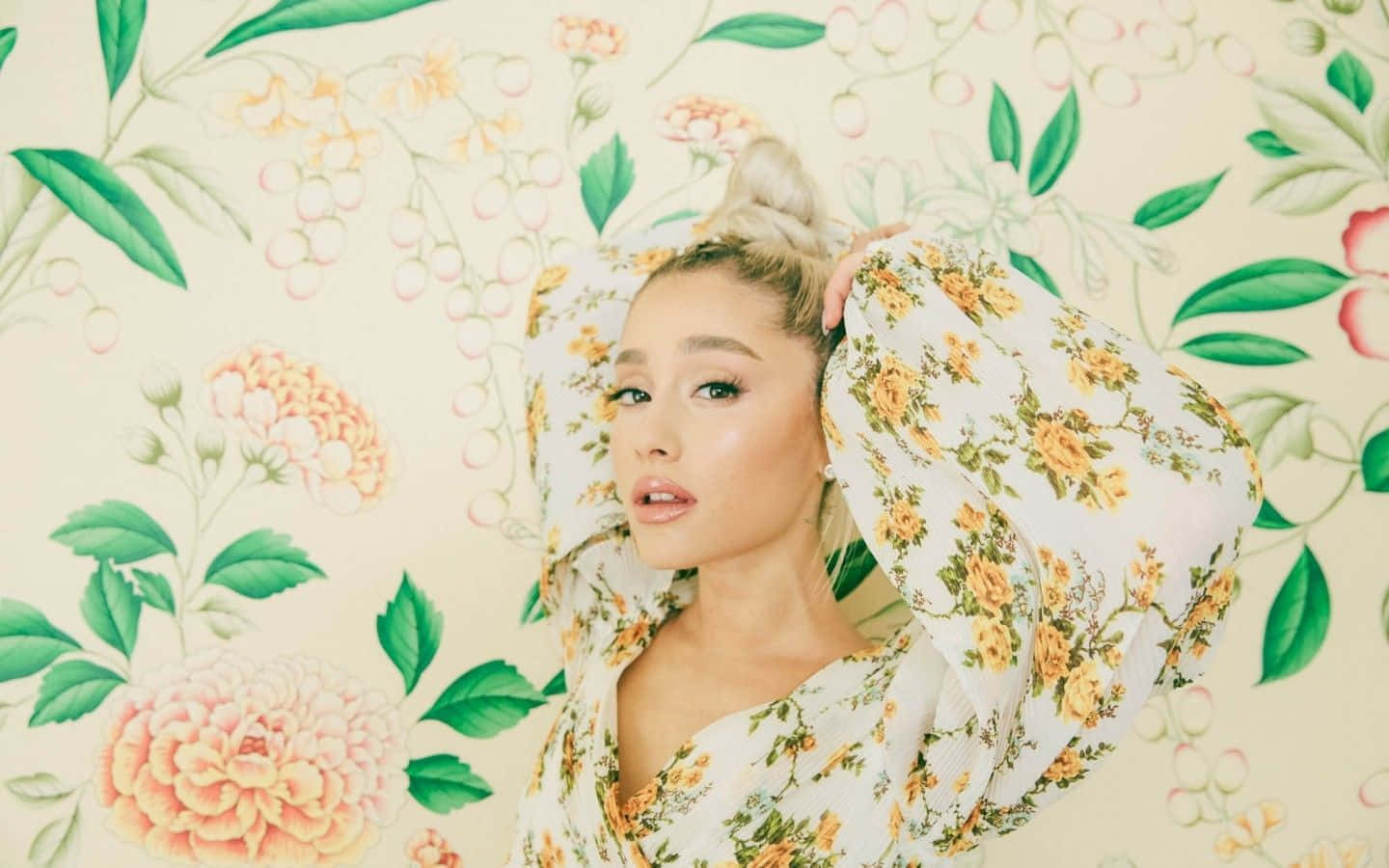 Ariana Grande Aesthetic 桌布 壁紙 — 一位穿著花卉圖案連衣裙的女性，在與之相配的柔和粉彩色調花卉壁紙前擺姿勢。
