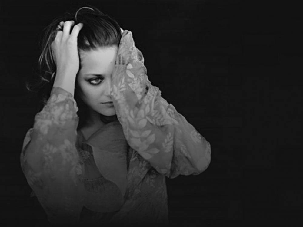 Singer 桌布 壁紙 — 一位穿著蕾絲服裝的女性，在深色背景下用一隻手遮住臉龐，同時凝視著鏡頭。