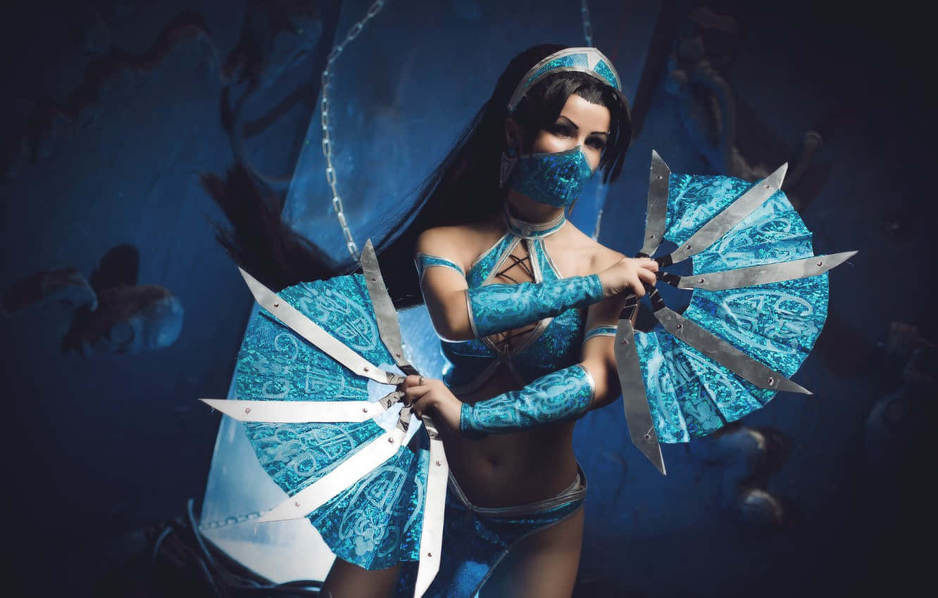 Mortal Kombat Cosplays 桌布 壁紙 — 一位穿著藍色圖案服裝的角色扮演者，在深藍色背景下揮舞著華麗的扇刃。