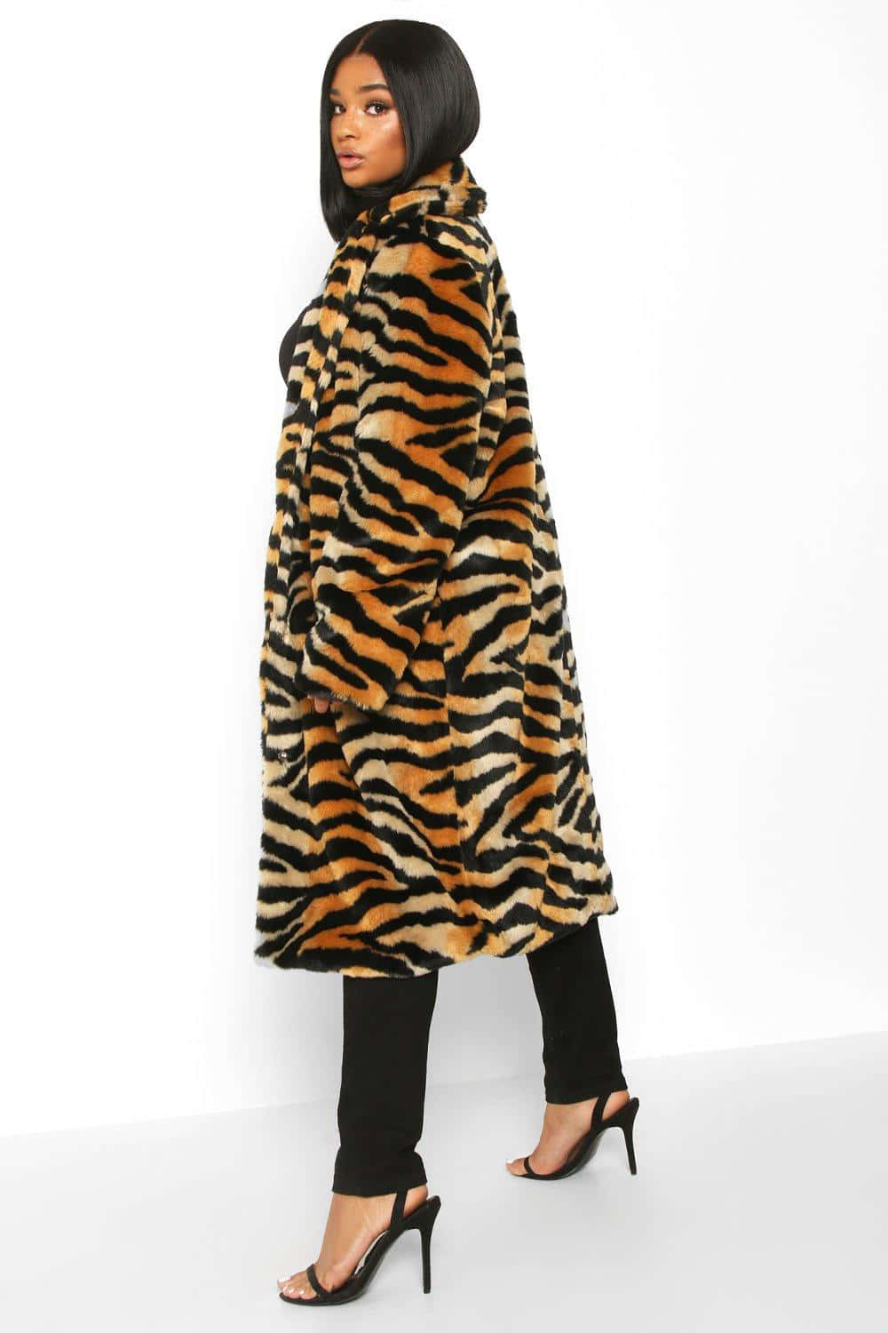 Animal Fur 桌布 壁紙 — 一位穿著虎紋仿皮草外套的女性，自信地站在純白的工作室背景前。