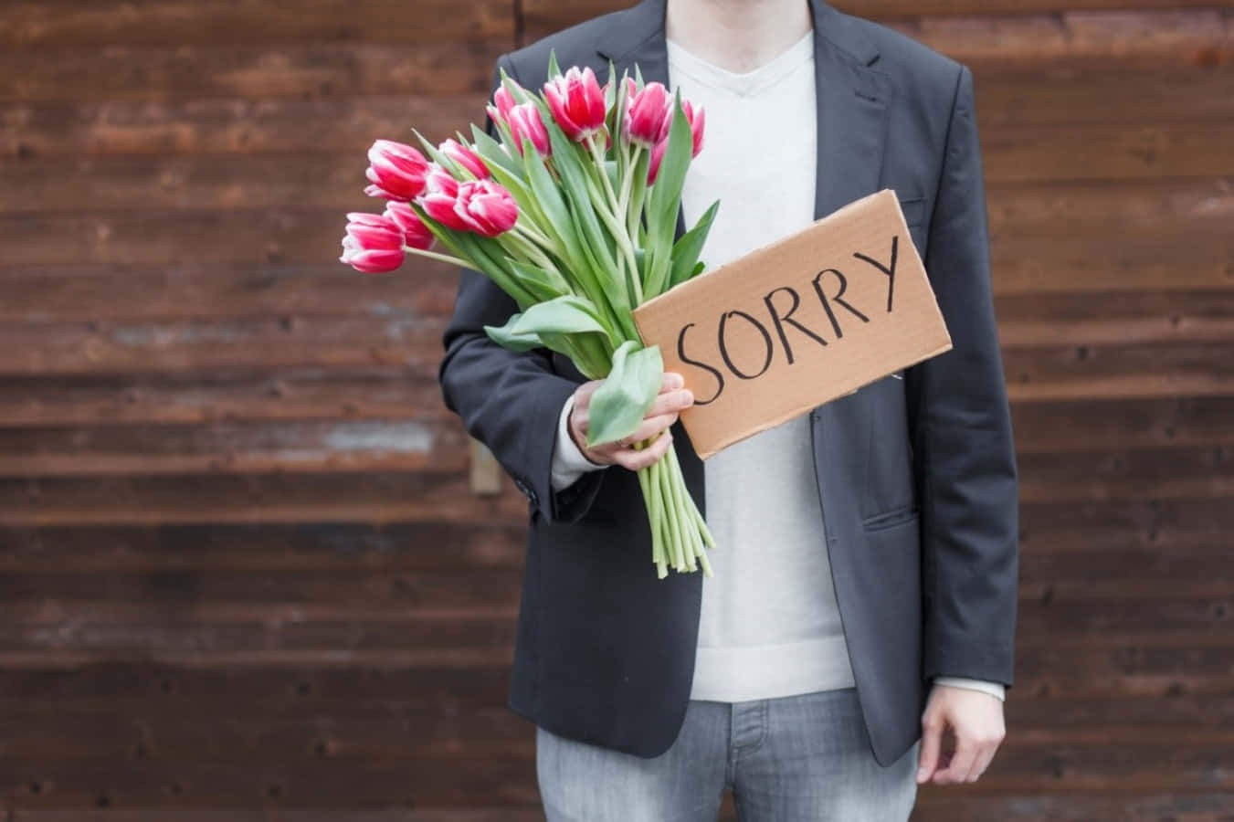 Flowers 桌布 壁紙 — 一位穿著西裝外套的人手持紅色鬱金香和一個寫著sorry的紙板標語，背景是木牆。