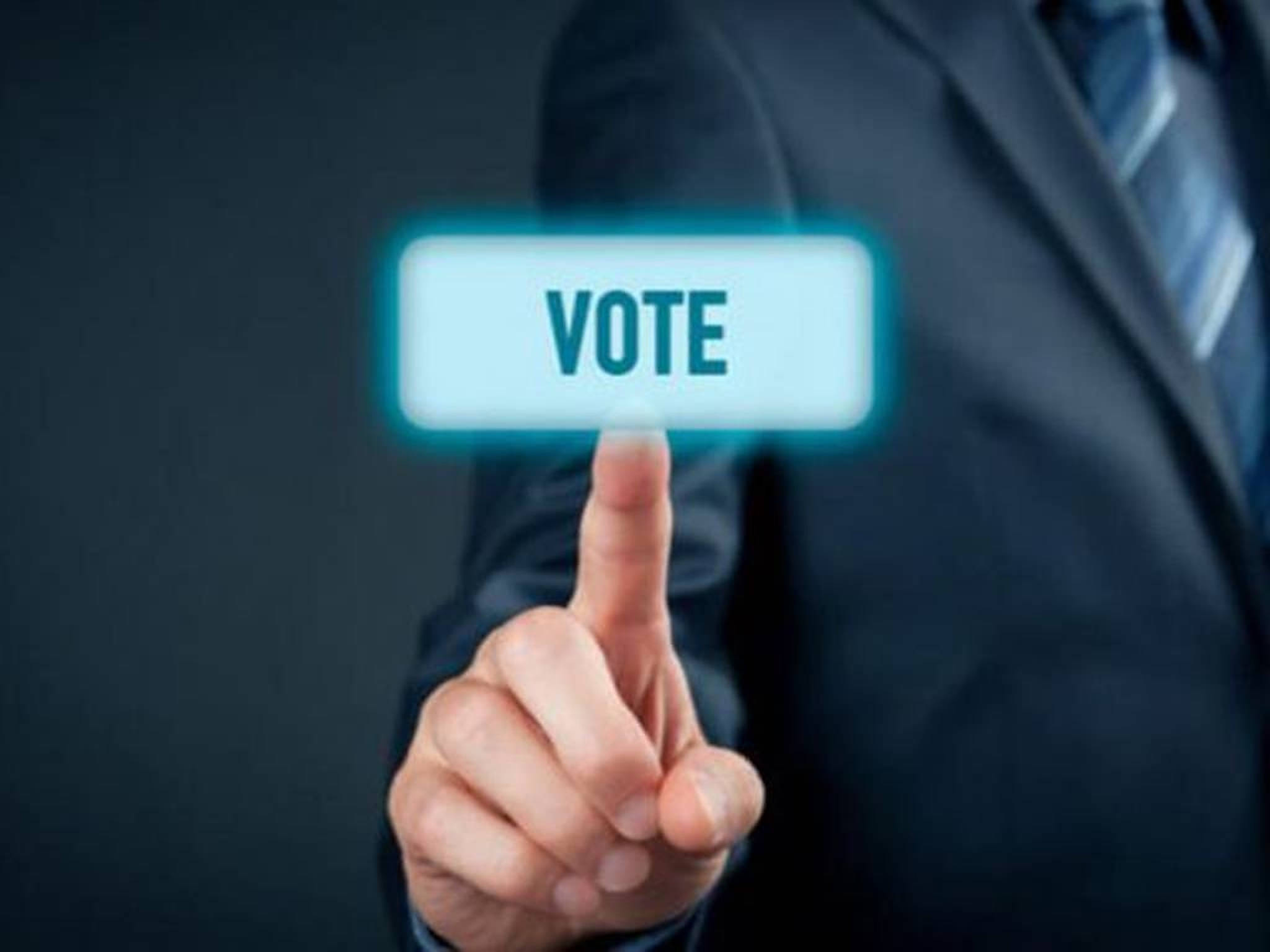 Election 桌布 壁紙 — 一位穿著西裝的商人正在黑暗背景的透明螢幕上按下發光的藍色「VOTE」按鈕。