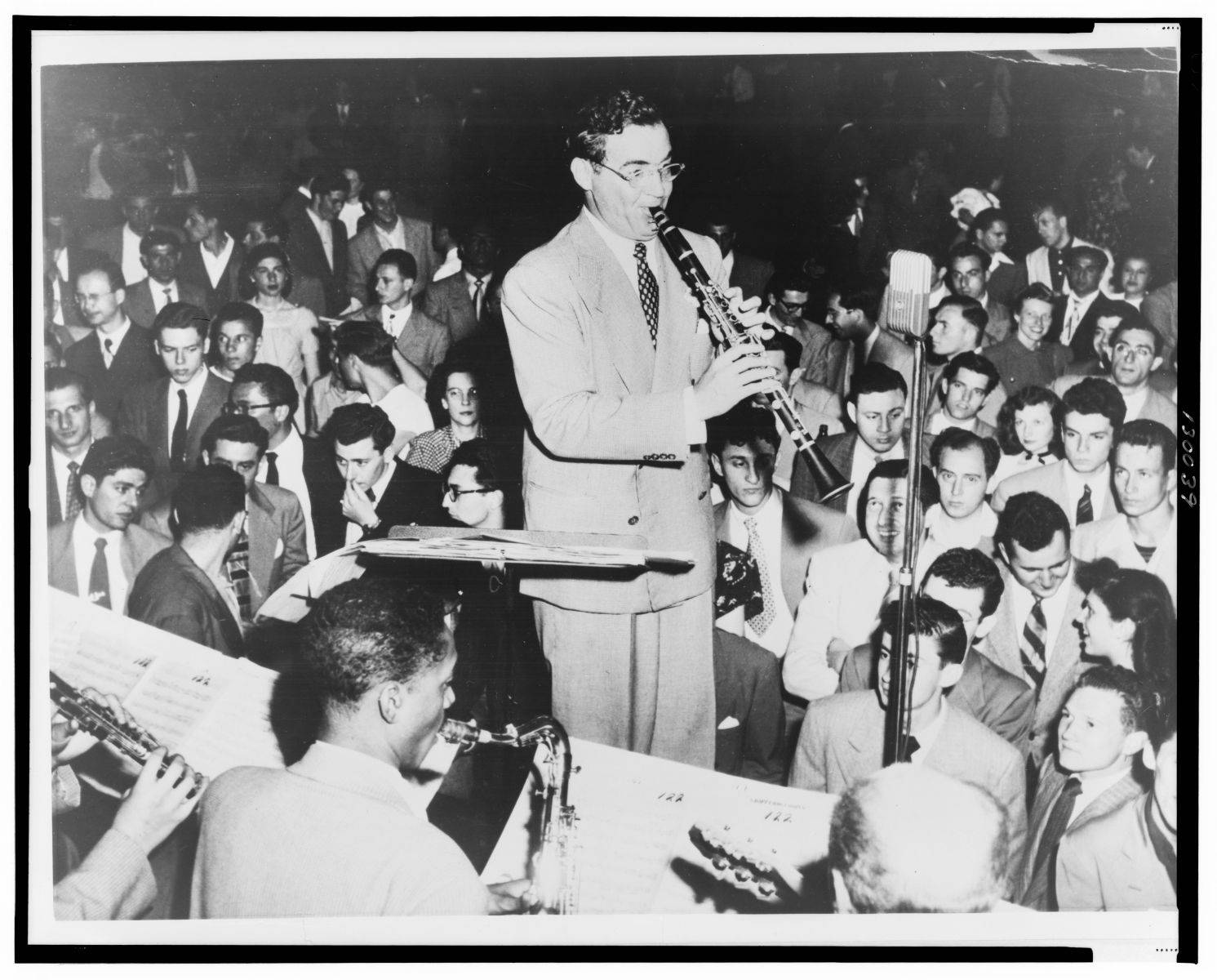 band 桌布 壁紙 — 一位穿著西裝的爵士音樂家在燈光昏暗的1940年代夜總會中，在投入的群眾面前演奏單簧管。
