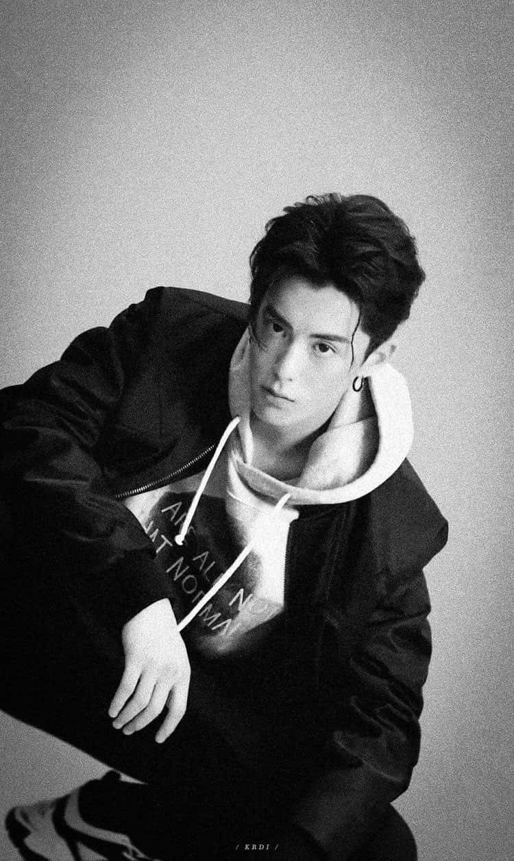 Dylan Wang 桌布 壁紙 — 一位穿著連帽衫和夾克的年輕男子，在純灰色背景前以黑白風格擺出嚴肅的表情。