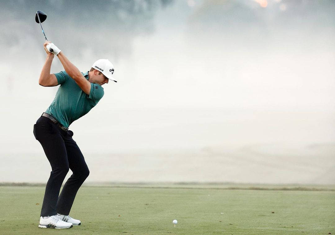 高爾夫 桌布 壁紙 — 一位穿著青綠色襯衫的高爾夫球手在霧氣籠罩的高爾夫球場上專注地揮桿，背景被霧氣覆蓋。