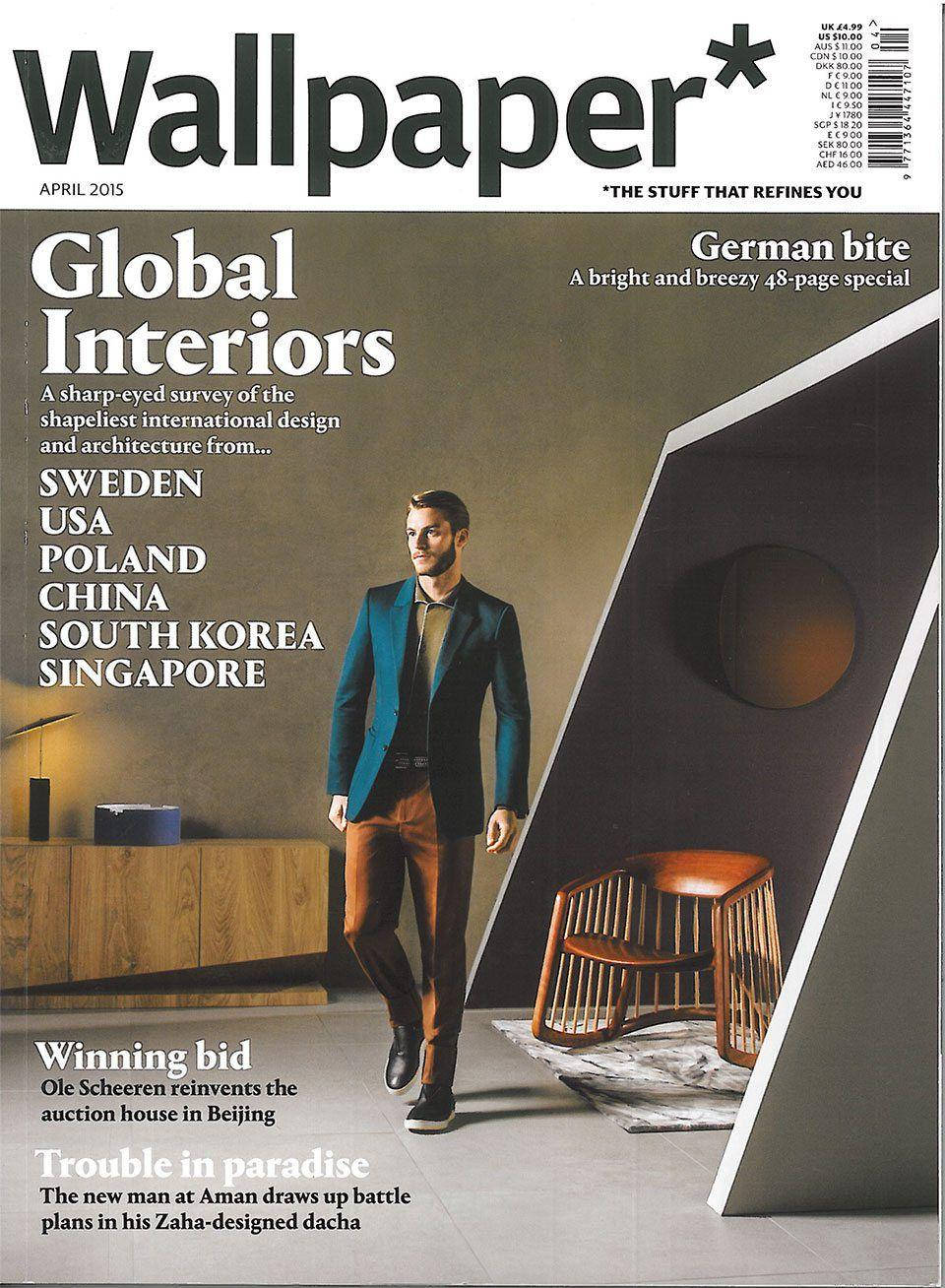 Magazine 桌布 壁紙 — 一位穿著青綠色西裝外套的時尚男士走過一個配有木製家具和幾何牆壁的現代室內空間。