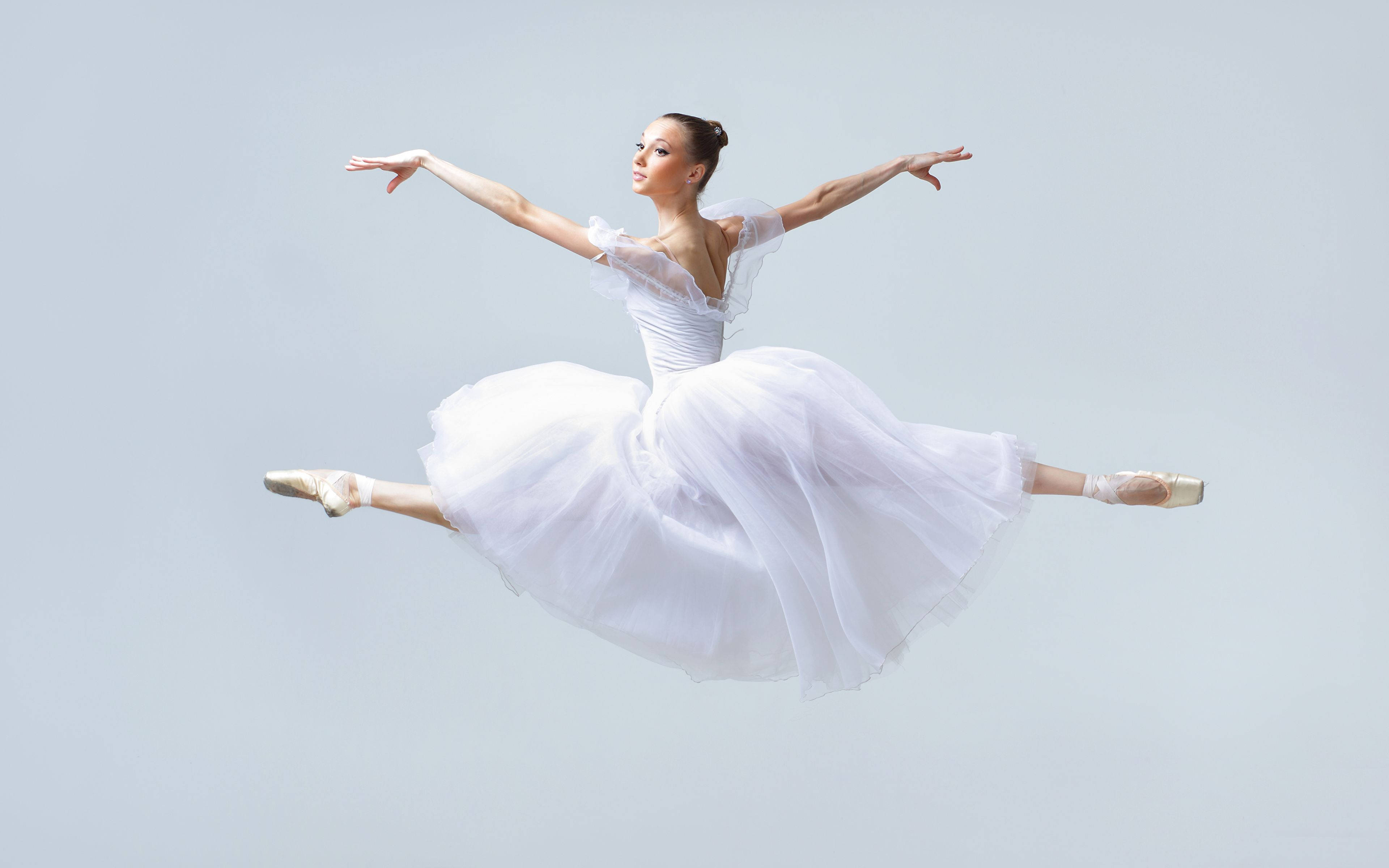 Ballet 桌布 壁紙 — 一位穿著飄逸白色芭蕾舞裙的芭蕾舞者在柔和的灰色工作室背景上優雅地跳躍。