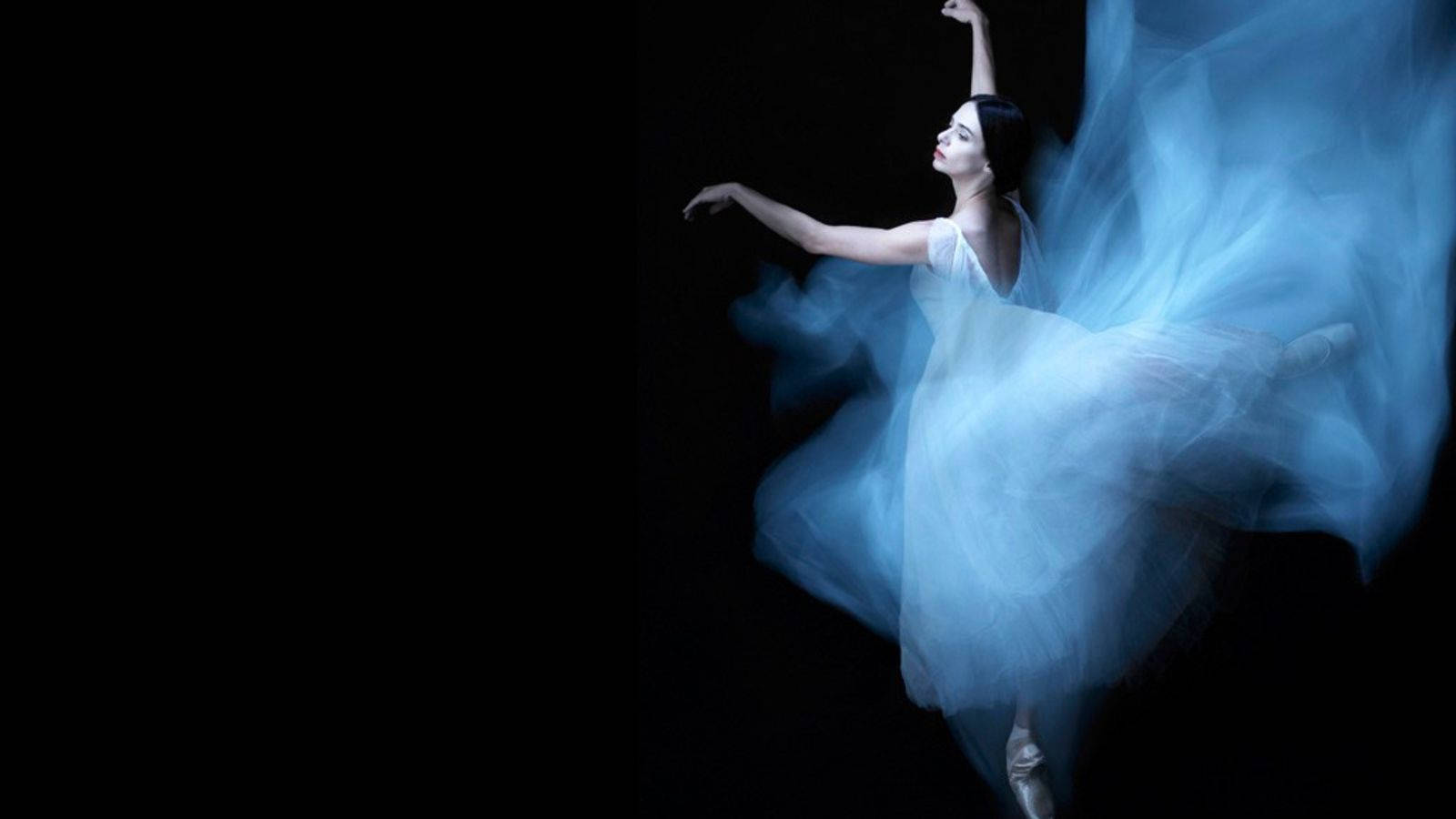 dancer 桌布 壁紙 — 一位穿著飄逸白色芭蕾舞裙的芭蕾舞者，在冷藍光照耀的漆黑背景前優雅旋轉。