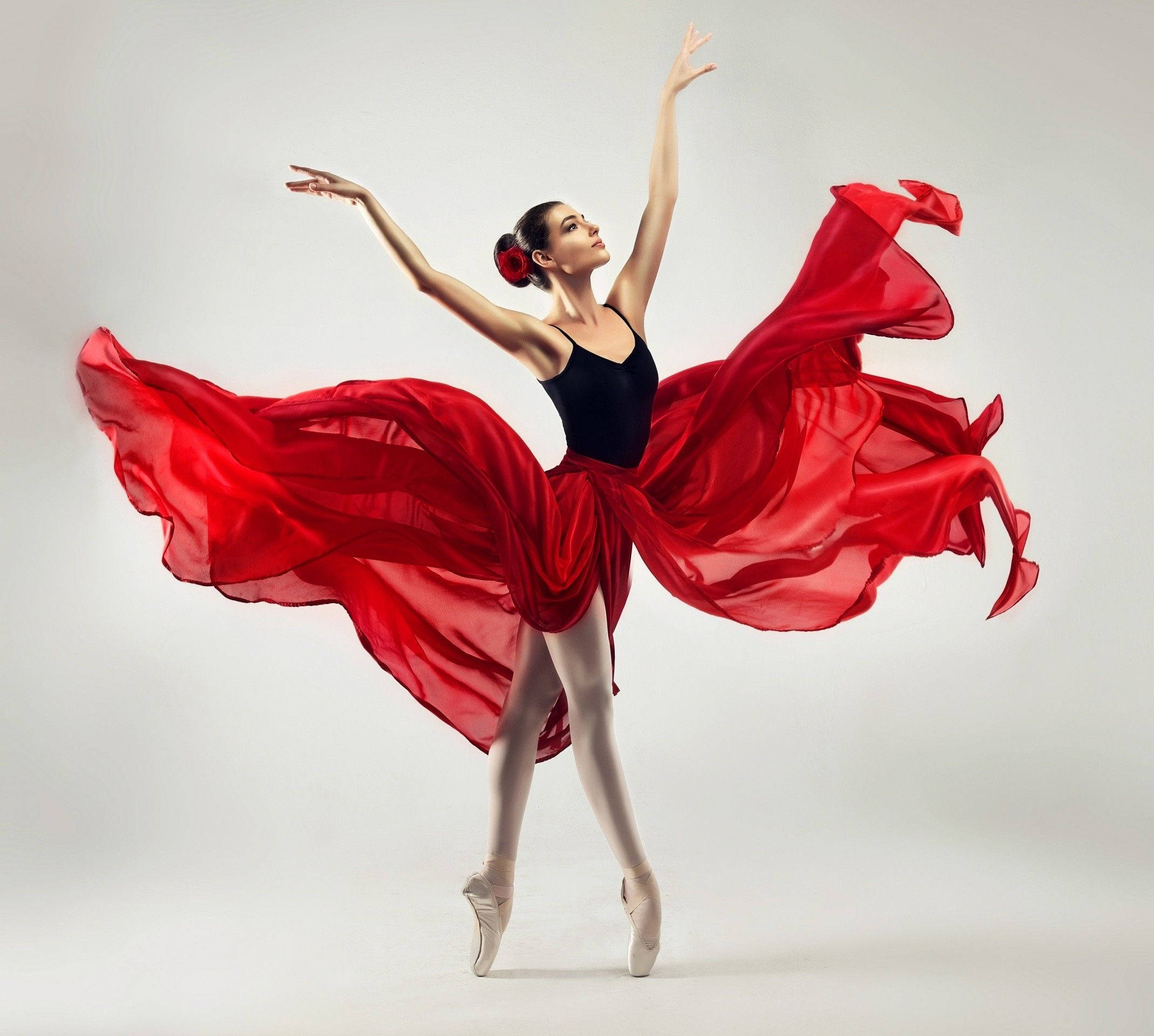 Ballet 桌布 壁紙 — 一位穿著飄逸紅裙的芭蕾舞者，在純白工作室背景前優雅地踮起腳尖跳躍。