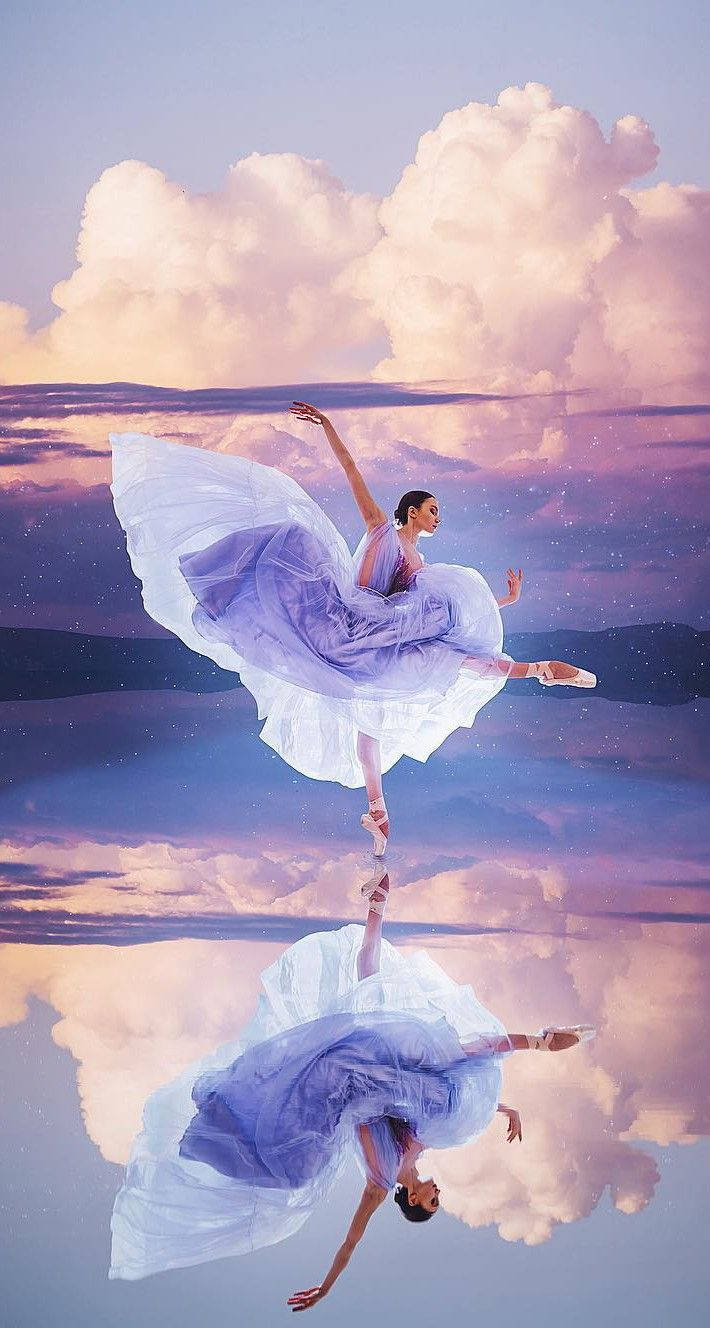 Ballet 桌布 壁紙 — 一位穿著飄逸薰衣草色連衣裙的芭蕾舞者優雅地跳躍在鏡面般的天空和雲朵之上，她的倒影完美地倒置在下方。