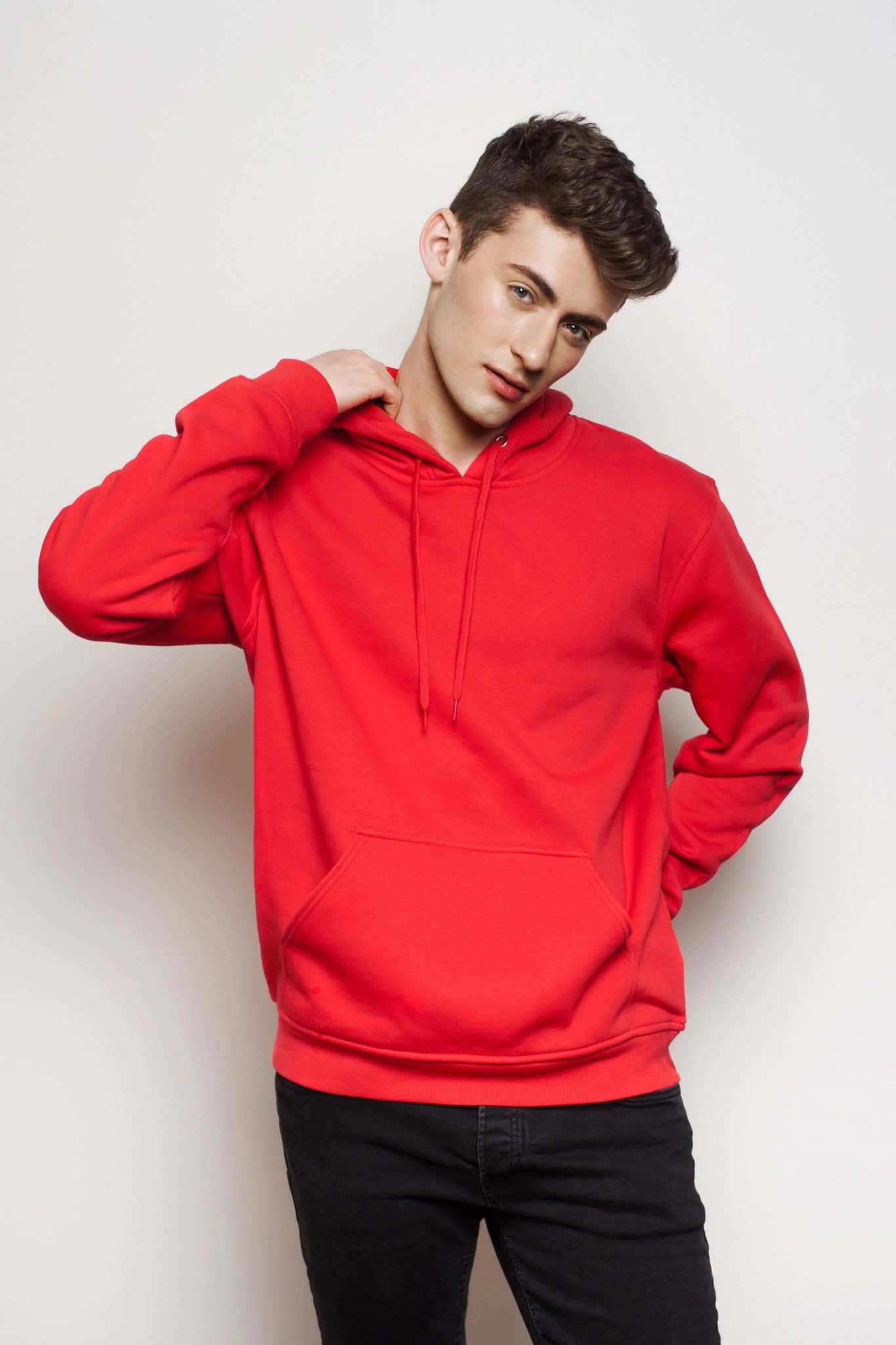 Red Hoodie 桌布 壁紙 — 一位穿著鮮紅色連帽衫的年輕男子，一手放在肩上，自信地在純白色背景前擺姿勢。