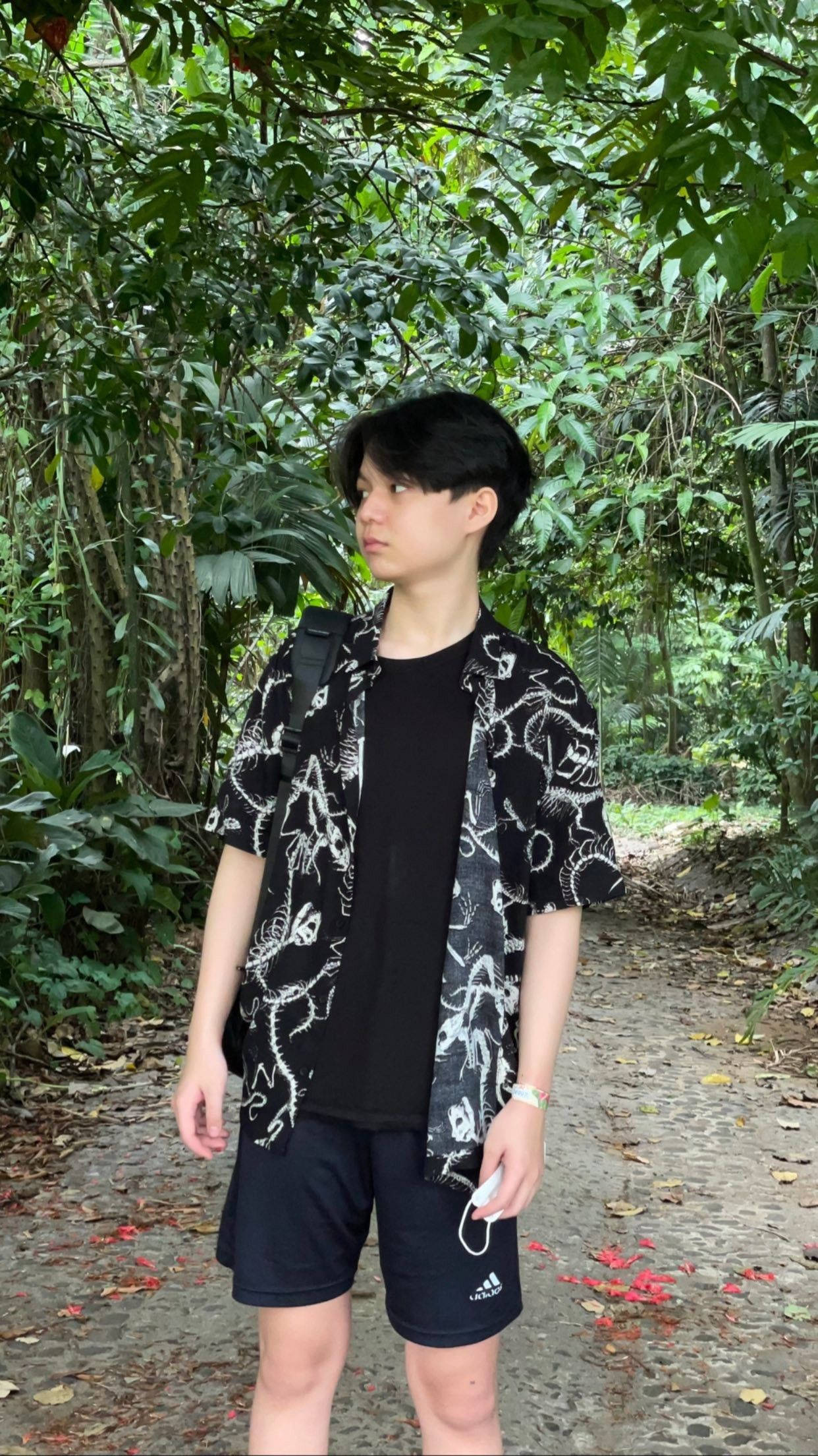 Team 桌布 壁紙 — 一位穿著黑白圖案襯衫的年輕人站在一條石徑上，周圍是茂密的綠色叢林葉子。