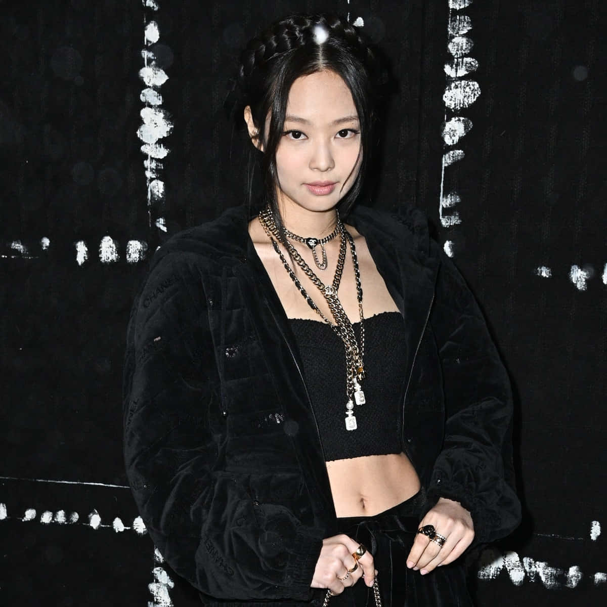 BLACKPINK 桌布 壁紙 — 一位穿著黑色天鵝絨外套和層疊鏈條的時尚女性，在帶有紋理的黑白背景前擺姿勢。