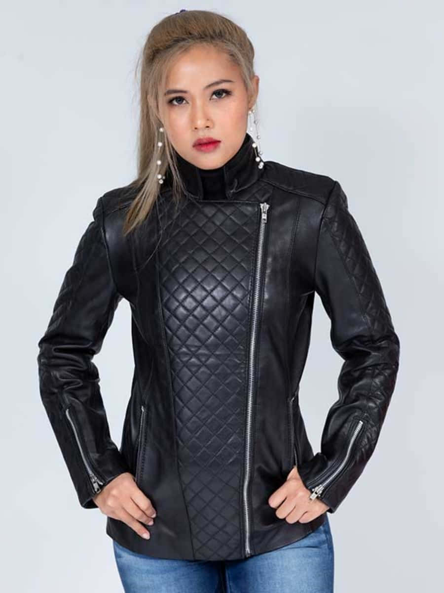 Black Leather 桌布 壁紙 — 一位穿著黑色絎縫皮革外套、配有銀色拉鍊的女性，自信地站在純白色背景前。