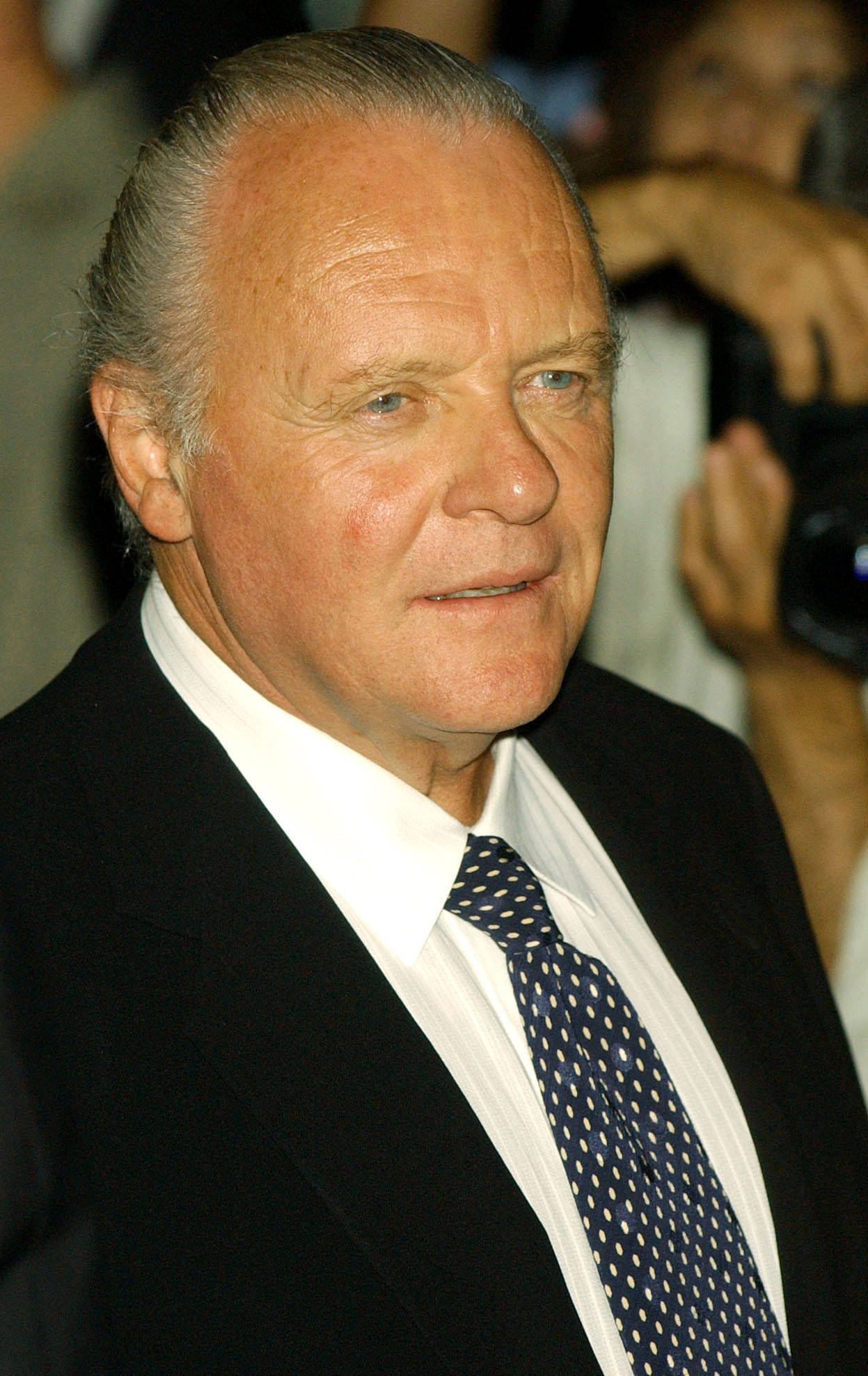actor 桌布 壁紙 — 一位穿著黑色西裝和波點領帶的尊貴長者在公共活動中的特寫肖像。