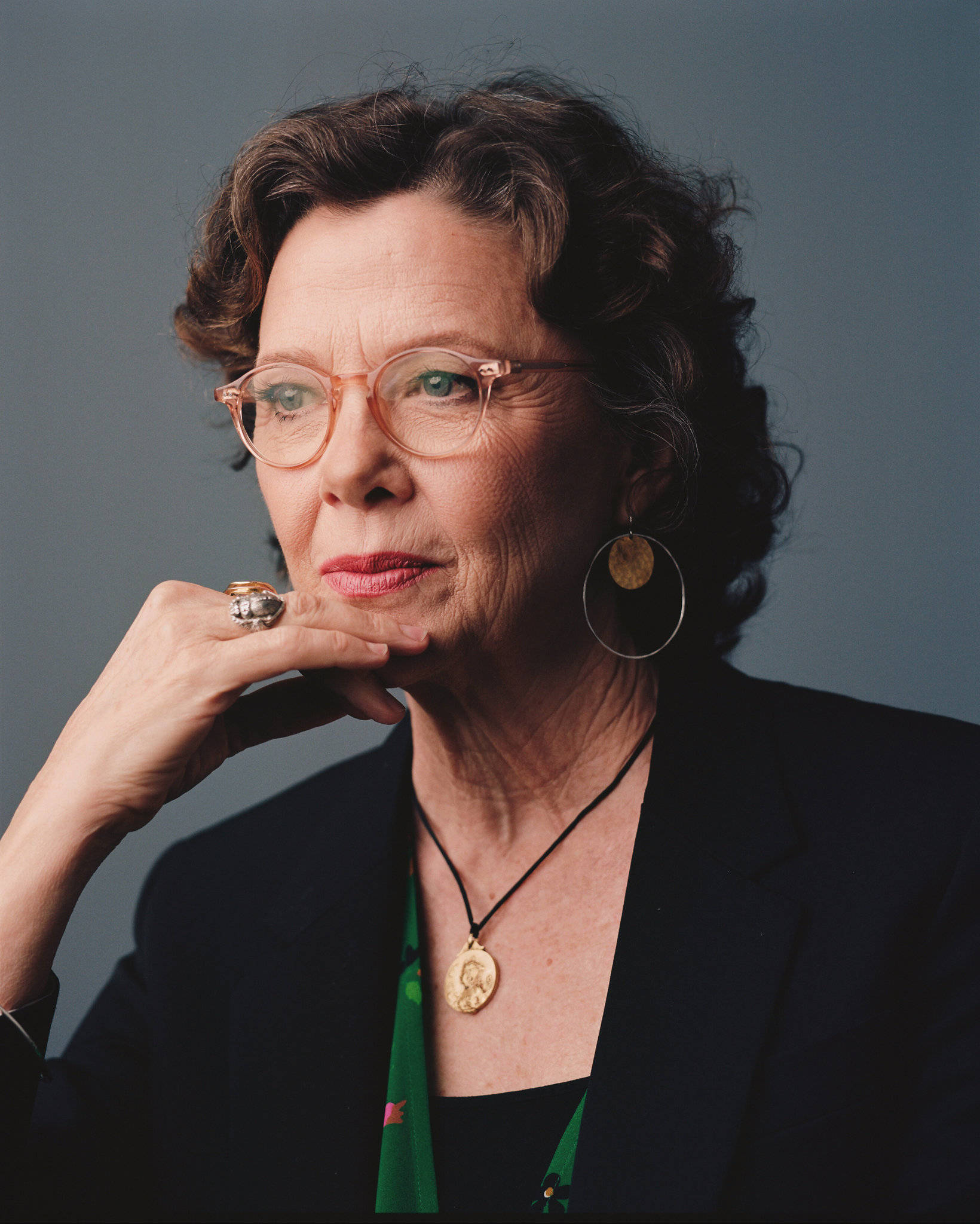 Celebrity 桌布 壁紙 — 一位端莊的老年婦女，捲髮戴眼鏡，手托下巴，背景為柔和的灰色。
