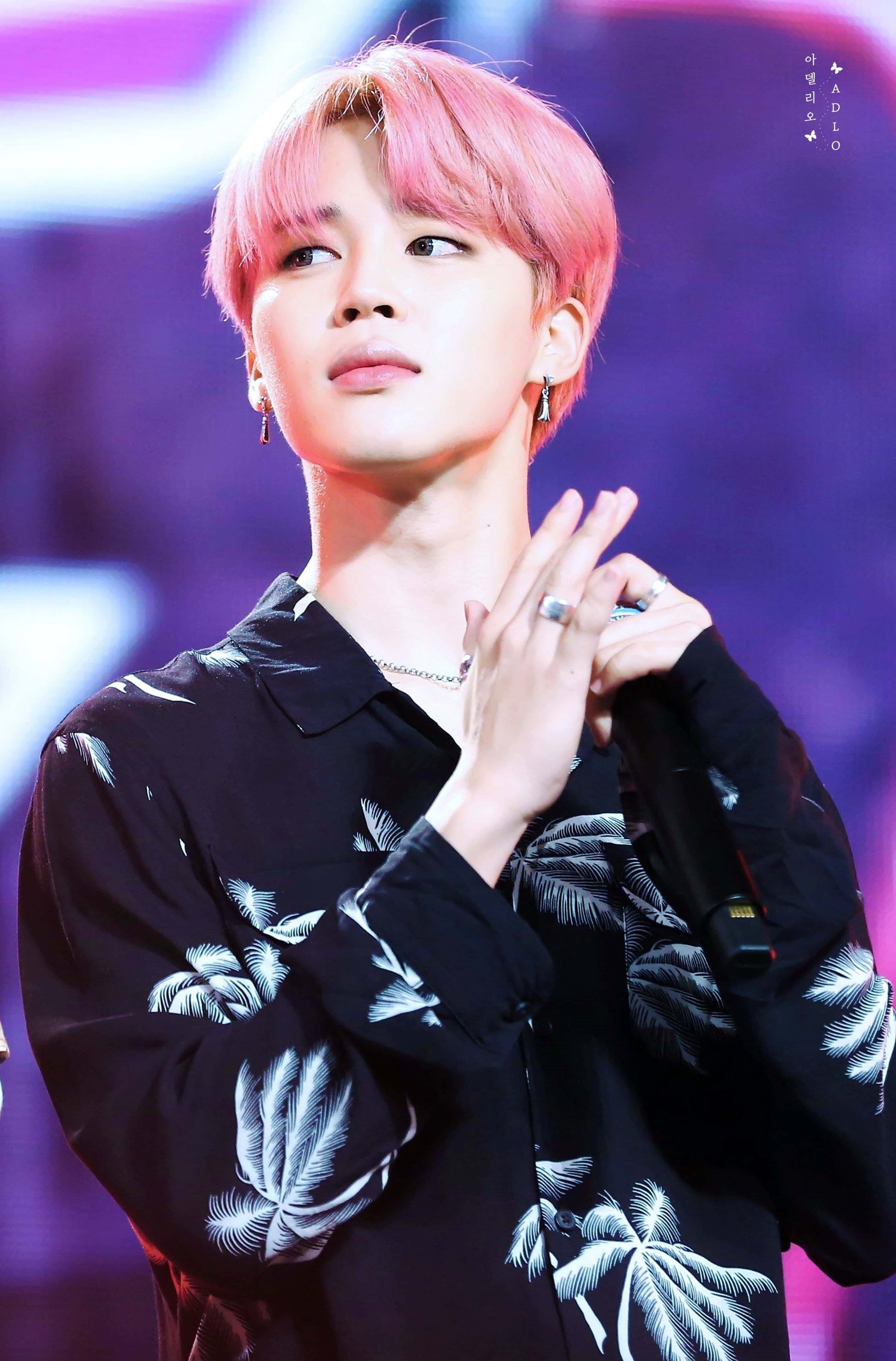 BTS 桌布 壁紙 — 一位粉紅色頭髮、身穿熱帶印花襯衫的年輕男子，在充滿活力的紫色舞台燈光下若有所思地擺姿勢。