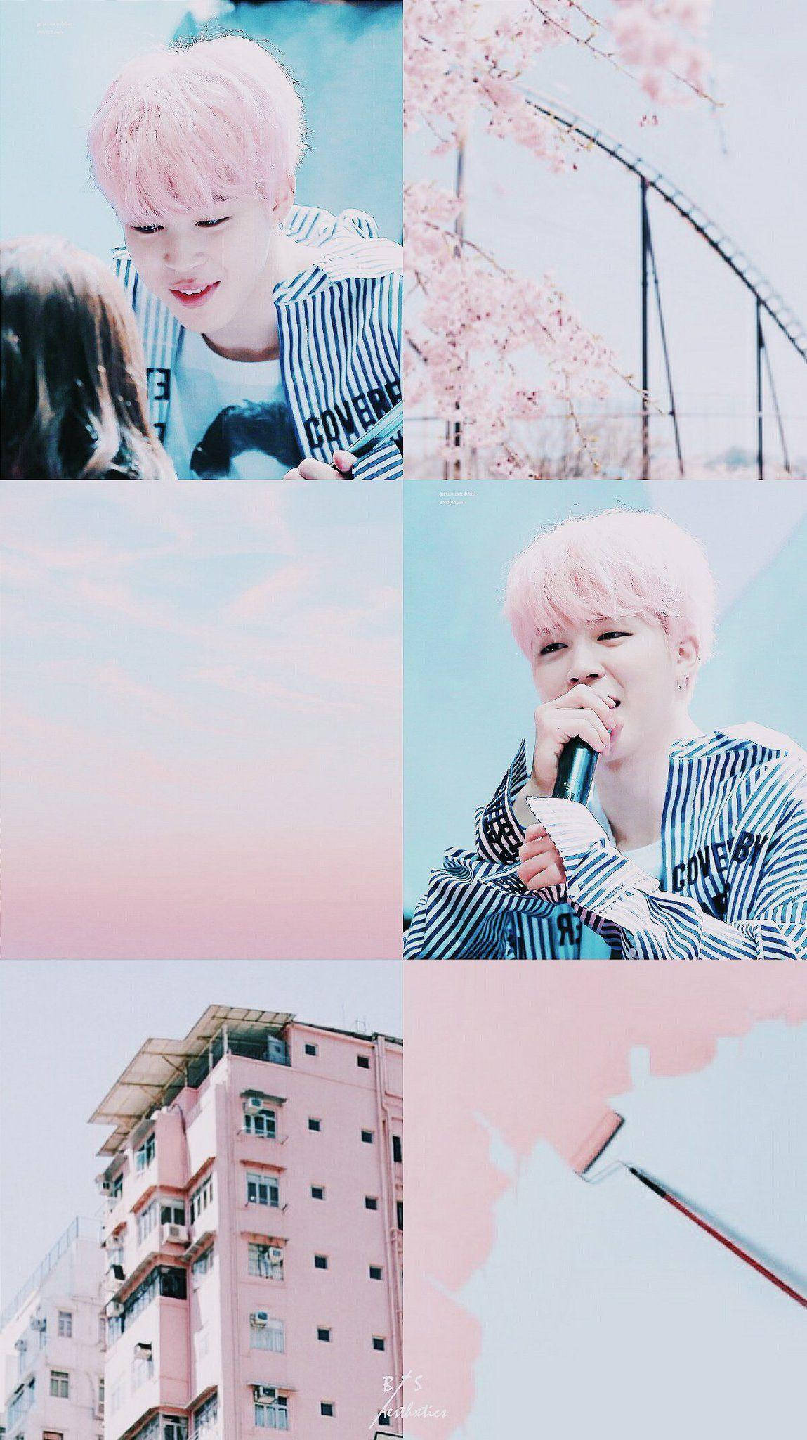Jimin Aesthetic 桌布 壁紙 — 一位粉紅色頭髮的K-pop偶像在柔和天空色調下，對著粉彩櫻花和粉紅色建築微笑唱歌。