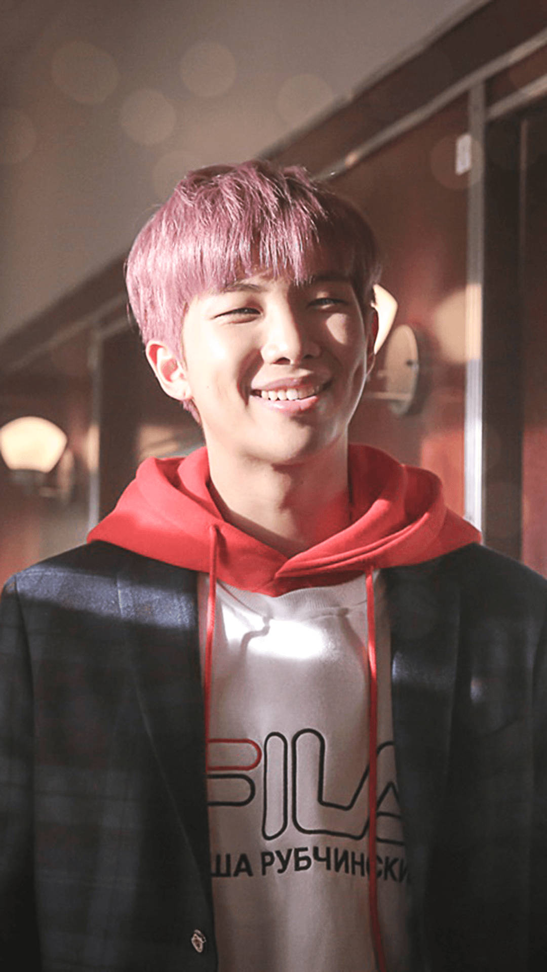 Namjoon 桌布 壁紙 — 一位粉紅色頭髮的年輕男子在室內穿著紅色連帽衫和黑色西裝外套，溫暖地微笑。