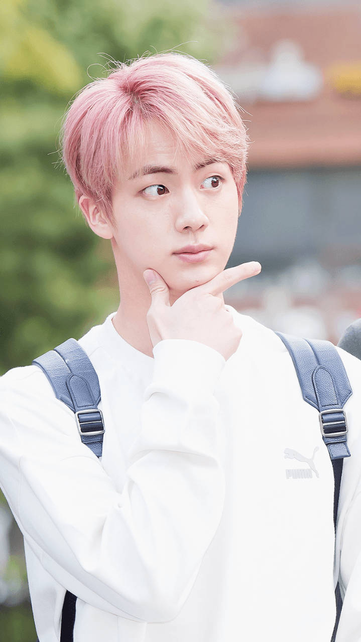 kim seok jin 桌布 壁紙 — 一位粉紅色頭髮的年輕男子穿著白色Puma運動衫，托腮沉思。