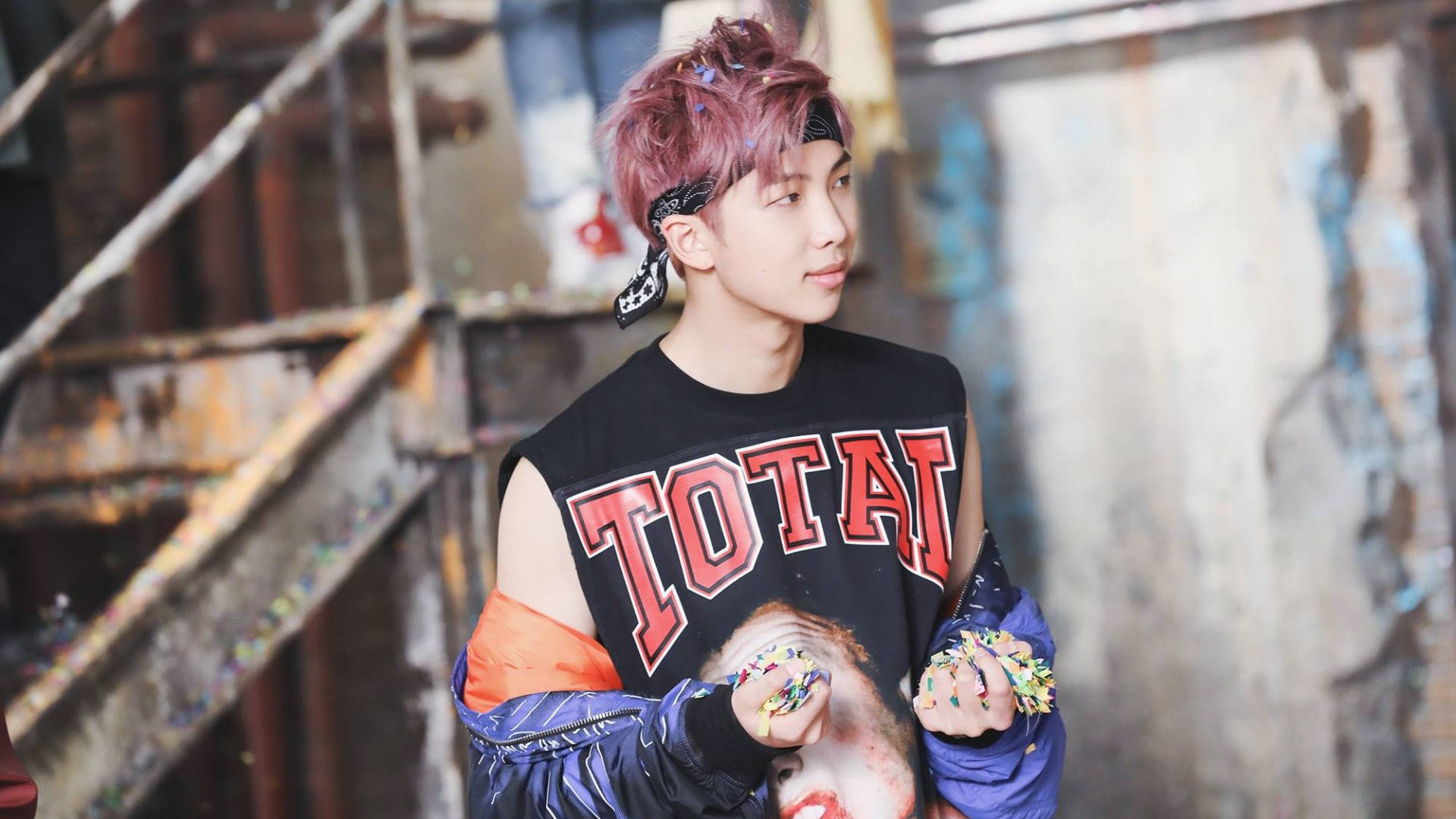 BTS 桌布 壁紙 — 一位粉紅頭髮、戴頭巾的年輕男子站在生鏽的工業小巷中，手持彩色亮粉。