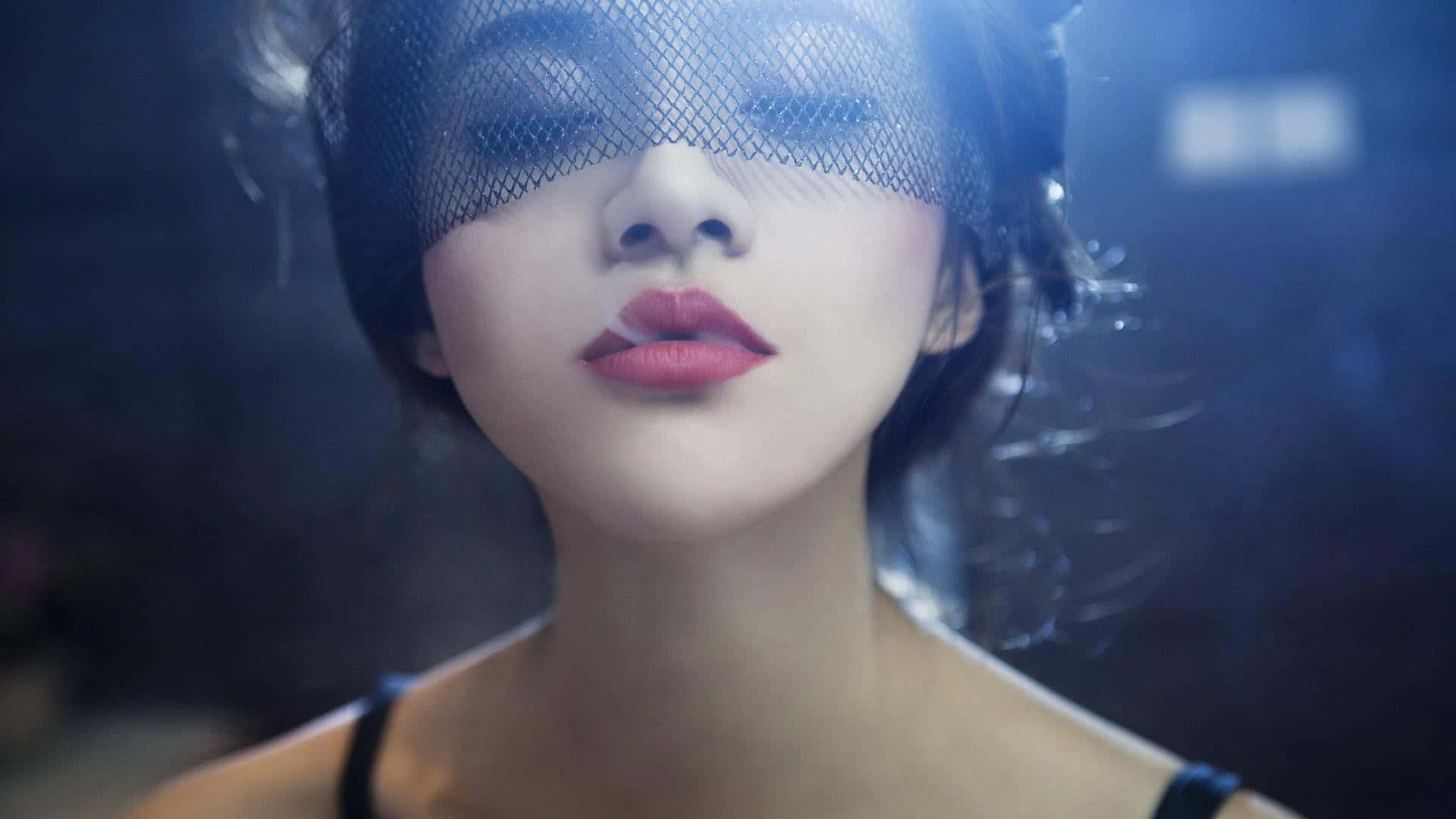 Mask 桌布 壁紙 — 一位紅唇女子，眼睛上戴著黑色網紗，在藍色燈光的攝影棚中柔和地凝視。