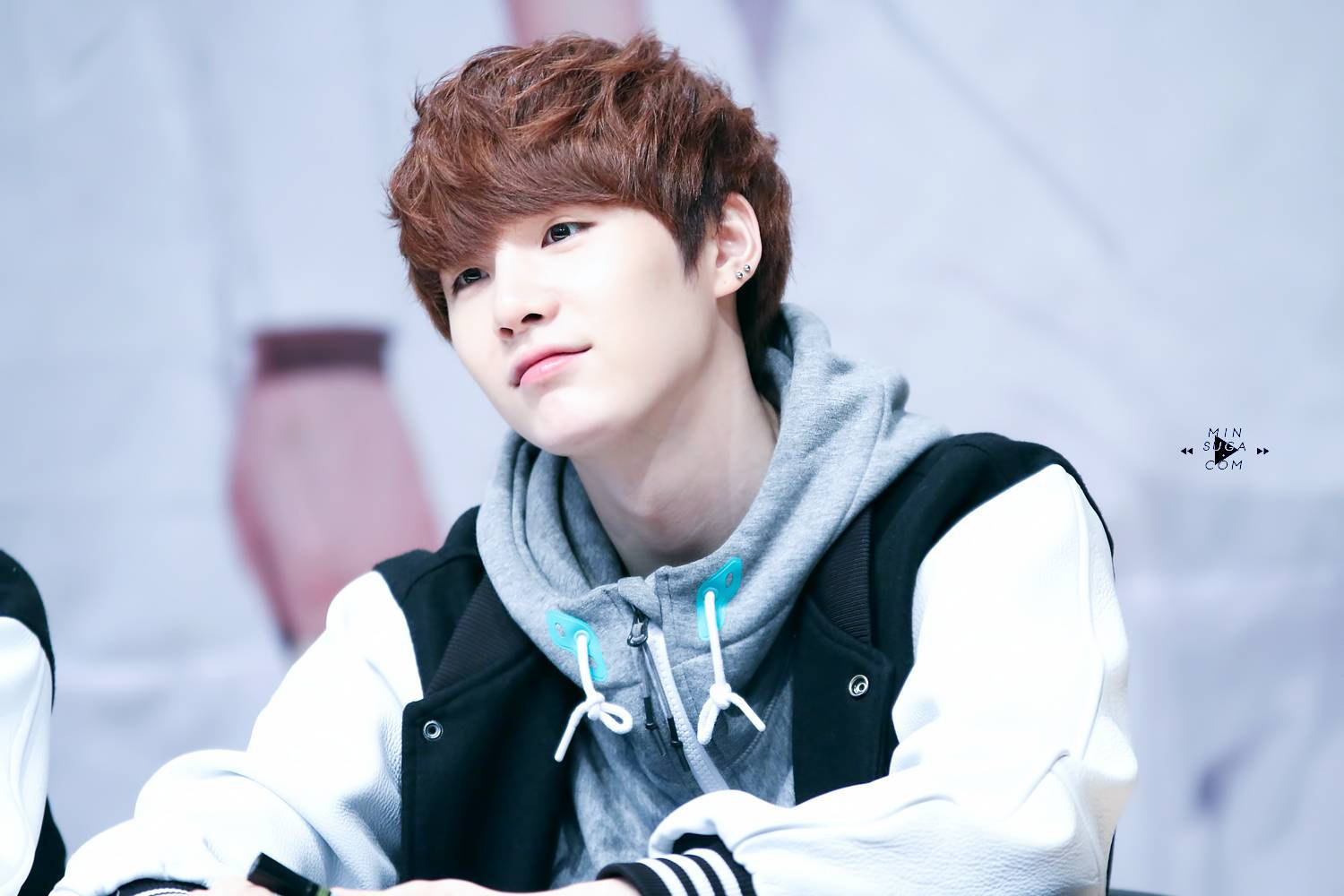 Suga Bts 桌布 壁紙 — 一位紅棕色頭髮的年輕男子穿著灰色連帽衫，外搭黑白夾克，若有所思地向上看。