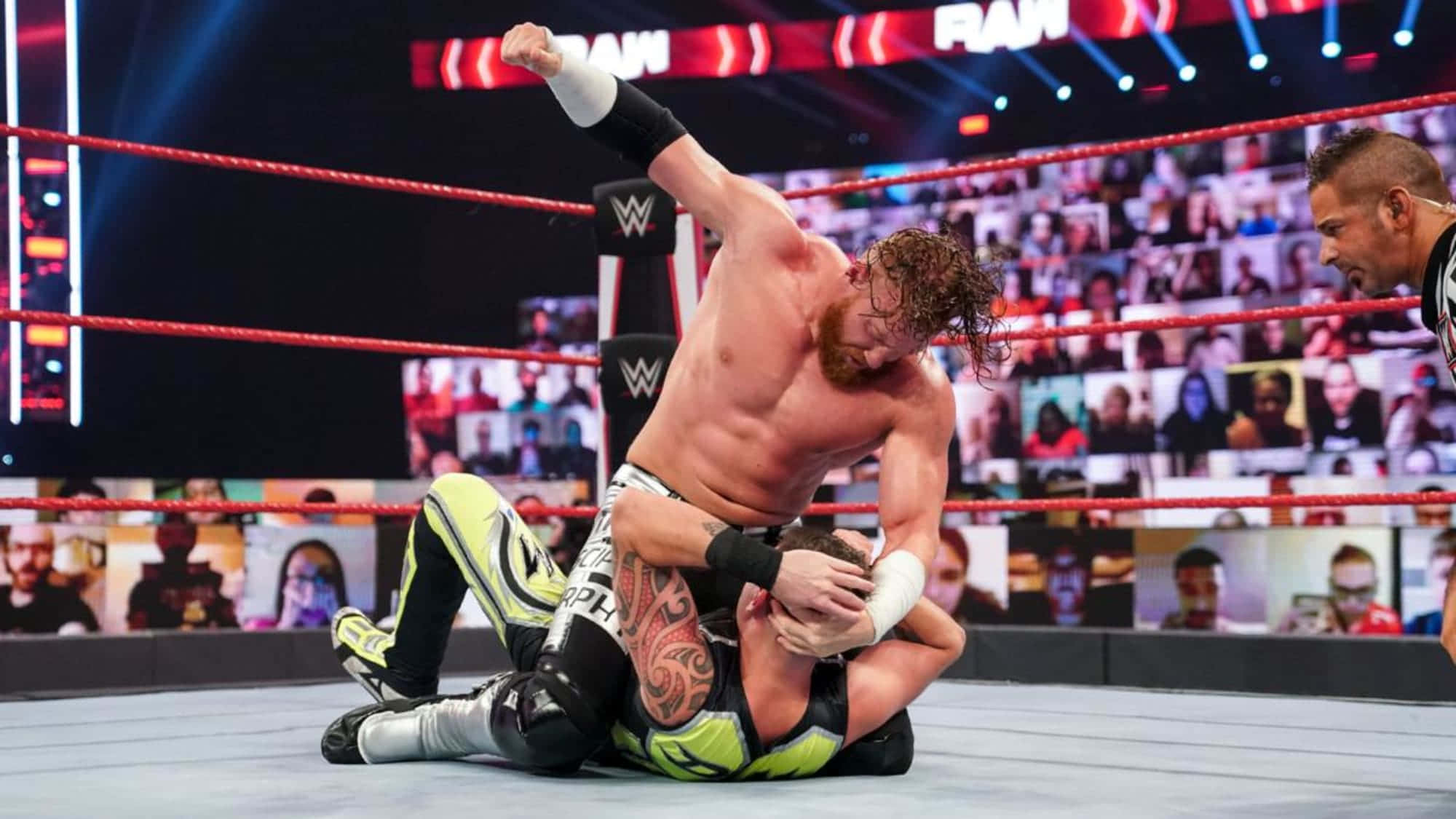 WWE 桌布 壁紙 — 一位紅色捲髮的摔角手在明亮的競技場燈光下，於摔角場中壓制對手。