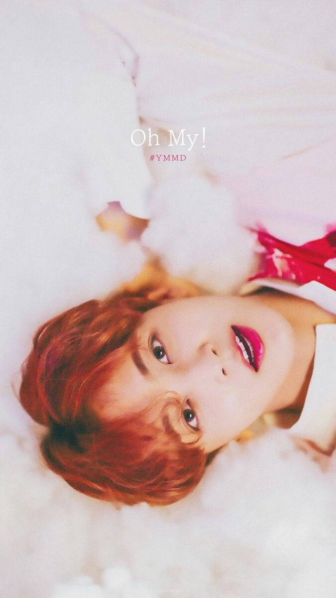 yoon jeonghan 桌布 壁紙 — 一位紅髮、嘴唇大膽粉紅的年輕人躺在柔軟的白雲上，帶著俏皮的表情向上看。