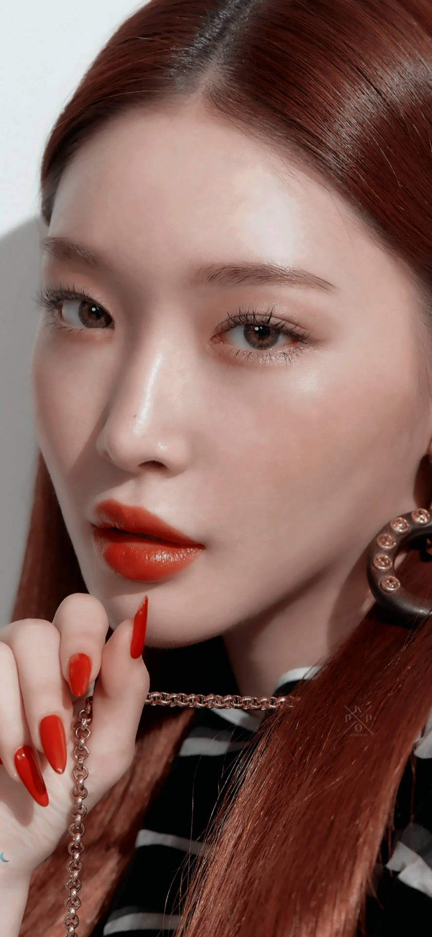 Chungha 桌布 壁紙 — 一位紅髮、塗著大膽紅唇膏的女性，在嘴唇附近拿著一條鏈條的特寫肖像。