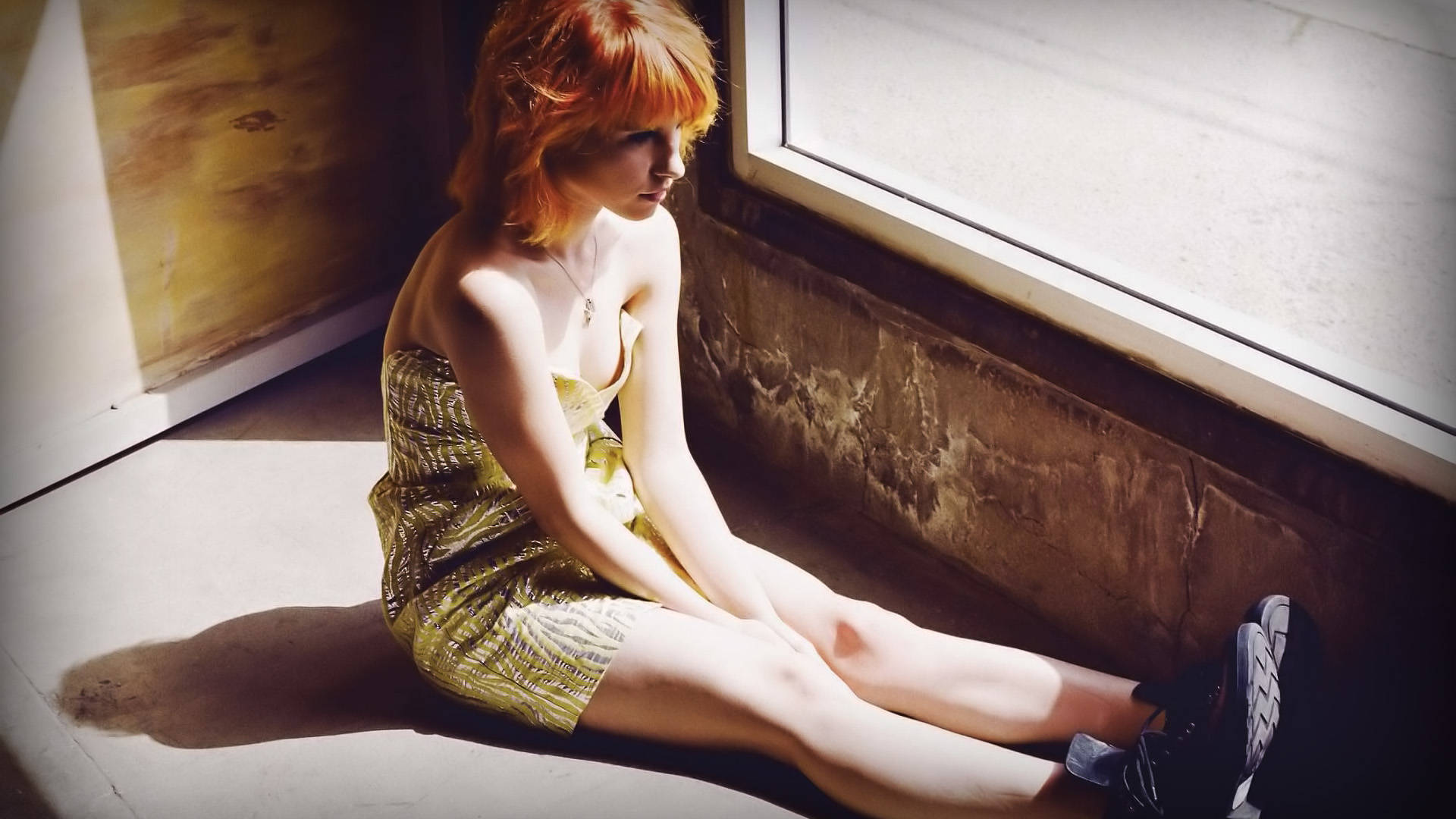 Hayley Williams 桌布 壁紙 — 一位紅髮女子赤腳坐在窗台上，身穿金色連衣裙，沐浴在溫暖的陽光中，投下長長的影子。
