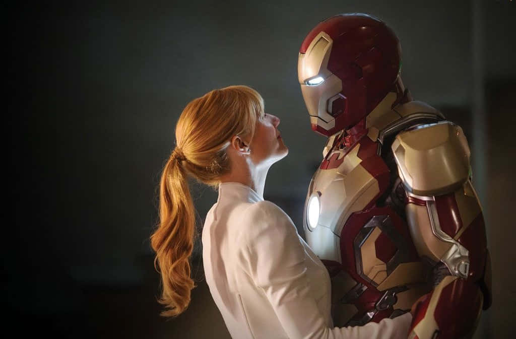 Iron Man Movies 桌布 壁紙 — 一位紅髮女性在昏暗的房間裡仰望鋼鐵人，他們的臉龐在親密時刻中靠近。