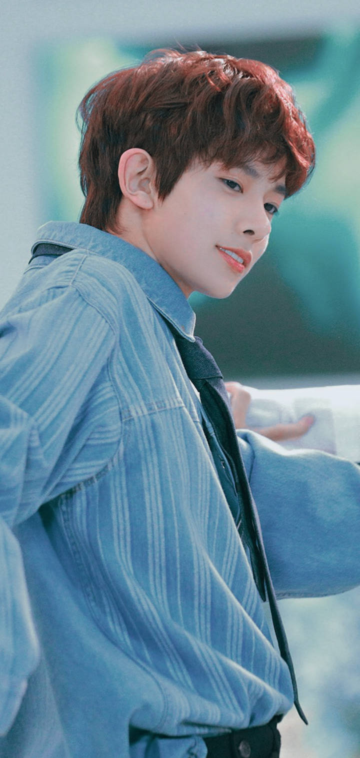 Kpop Aesthetic 桌布 壁紙 — 一位紅髮年輕男子穿著藍色條紋襯衫，在模糊的藍綠色背景下溫柔微笑。