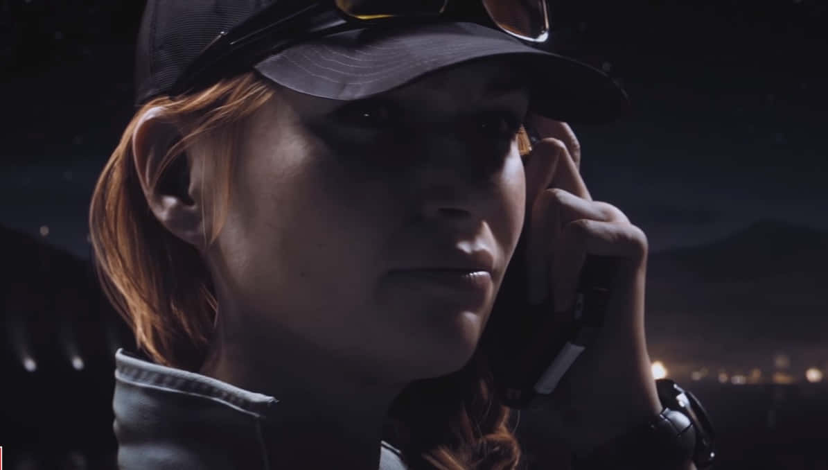 Rainbow Six Siege Ash 桌布 壁紙 — 一位紅髮戴帽子的女士在繁星點點的夜空下，背景是遠處的城市燈光，正在講電話。